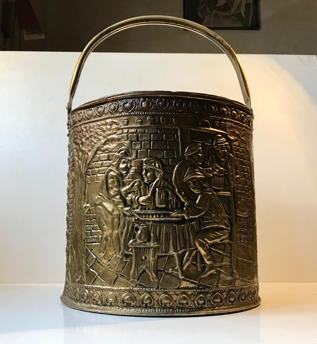 Embossed brass bucket for firewood or fireplace tools. It's a nice big one and would also make a good wastebasket or trash can. It depicts medieval party/social scenes. The black paint on the interior is worn, and there's a bit patina to the brass.