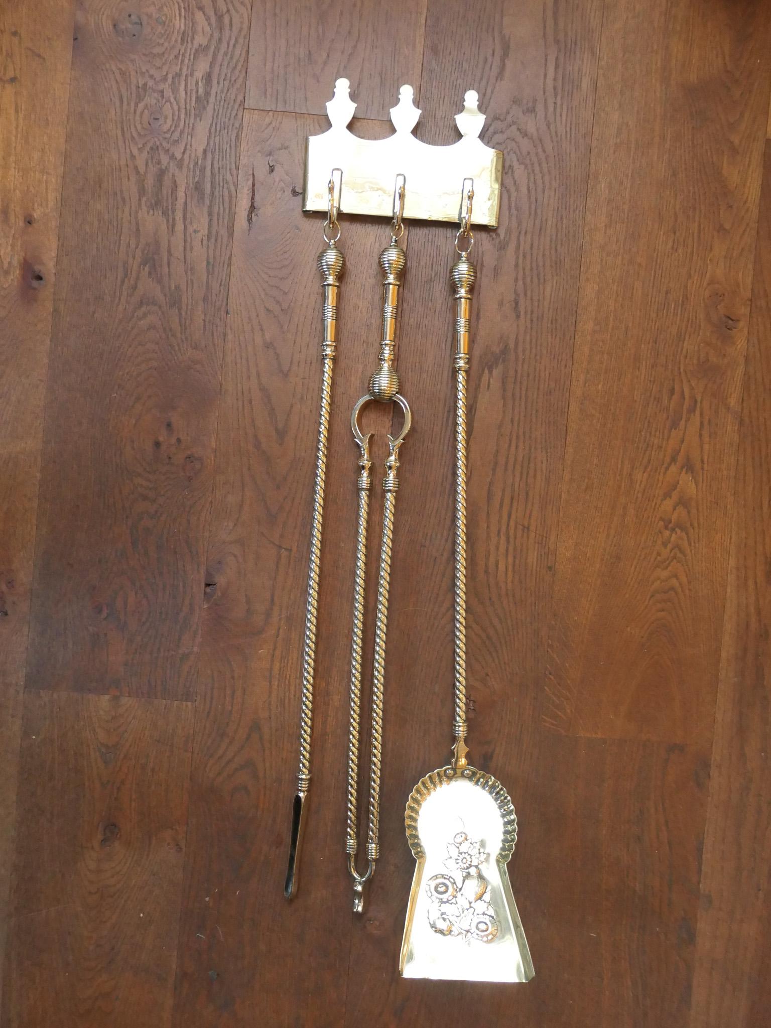 19th century Dutch victorian fireplace tool set consisting of a fireplace tongs, fire poker, a fireplace shovel and a hanger. The set is made of polished brass. They are in a good condition and are fully functional.