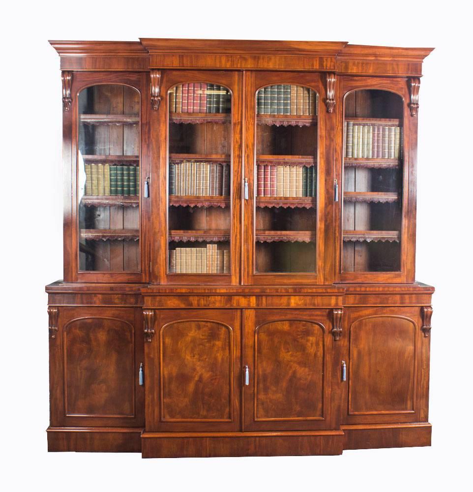 This is a beautiful antique early Victorian top quality flame mahogany four-door breakfront bookcase, masterfully crafted in rich solid mahogany, circa 1860 in date.

This magnificent bookcase features four arched top glazed doors in the upper