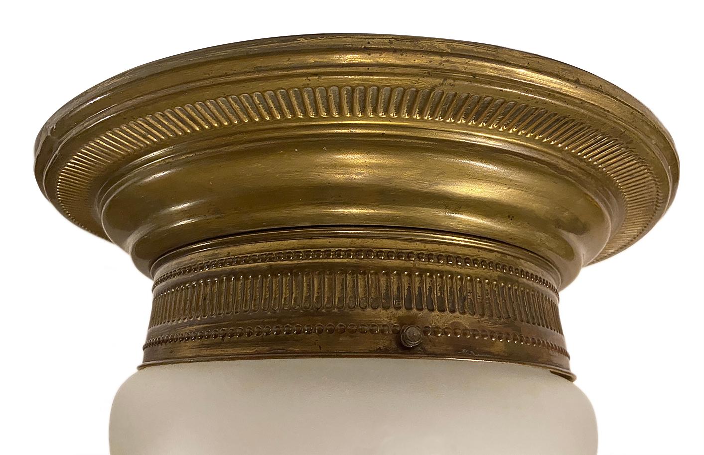 An English circa 1920s repoussé brass flush mounted light fixture with frosted glass inset.

Measurements:
Diameter 15 1/2