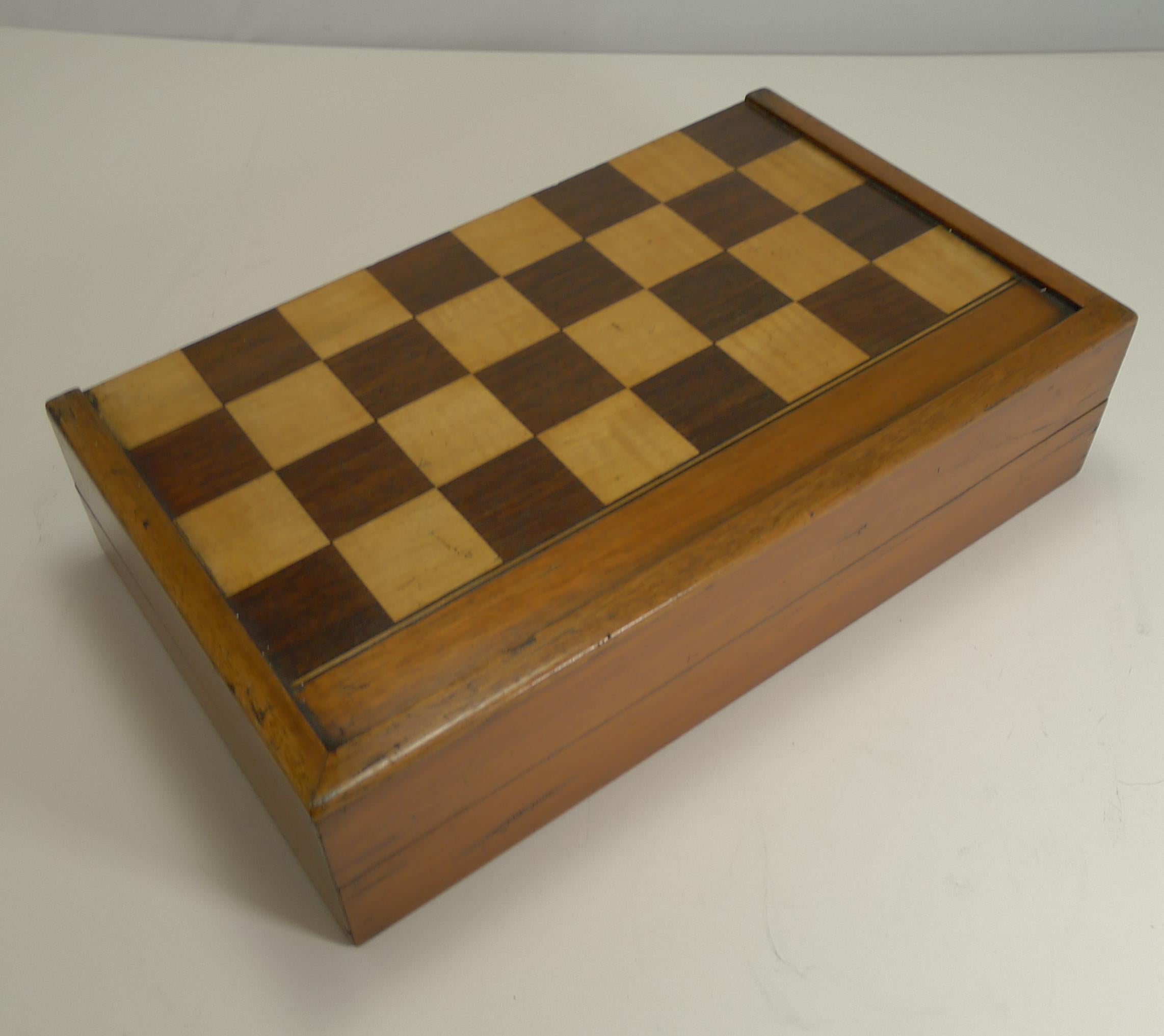This antique English folding games board is made from mahogany and inlaid with mahogany and fruitwood tiles, each measuring 1 1/2