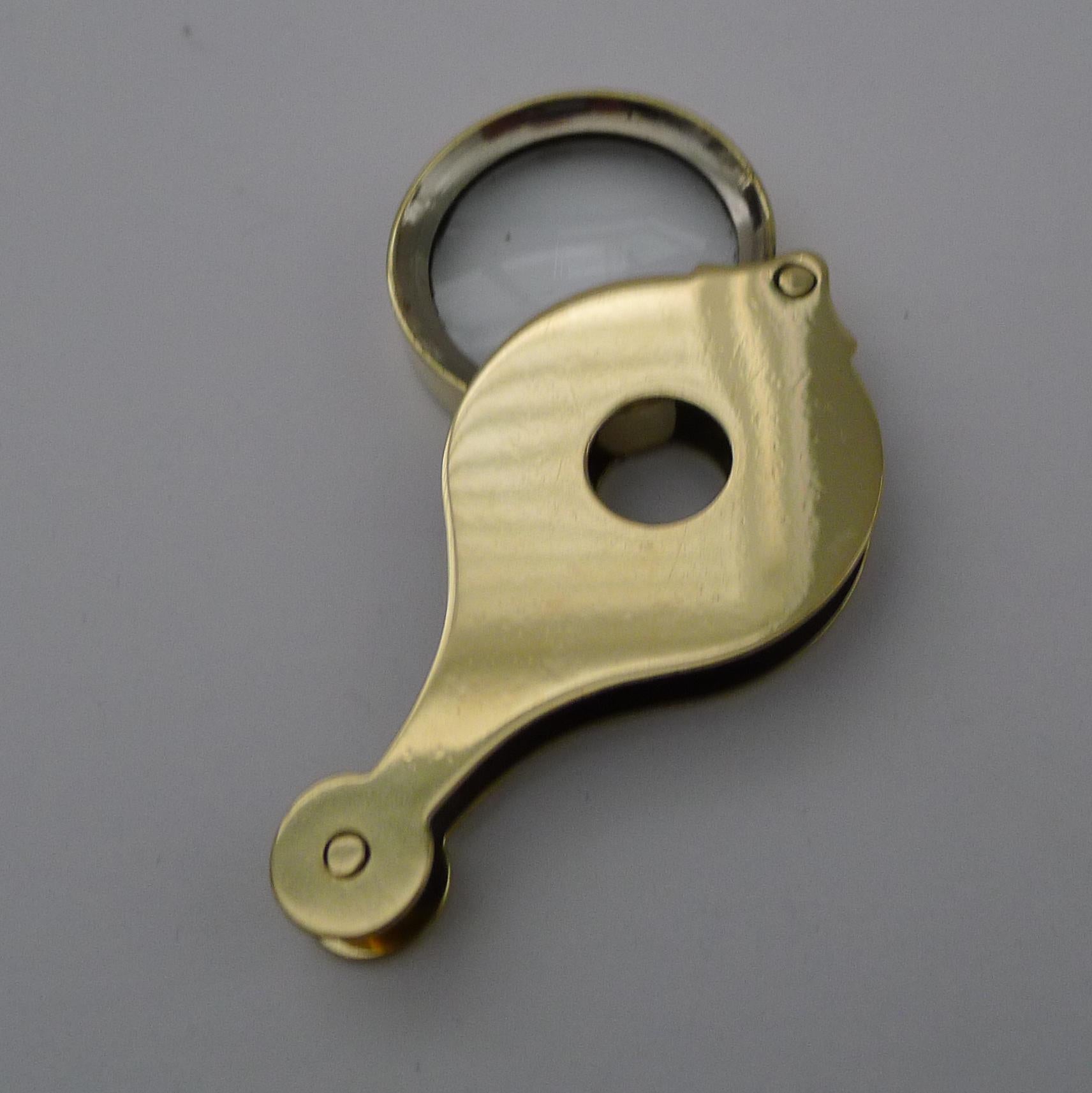 An unusual Edwardian Folding magnifying glass, the polished brass case having a hole in the centre allowing it to picked up and the magnifying glass being able to be used looking through the hole. If a larger magnifier is required, it can be