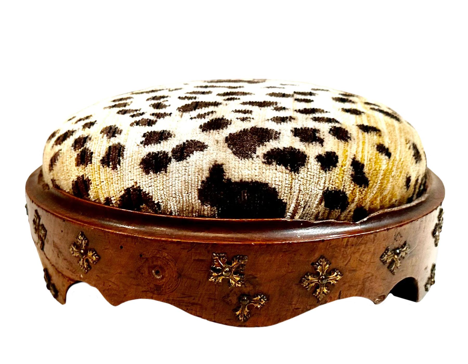 A lovely 1880s round carved wooden footstool with brass.  Upholstered in 1970s silk Scalamandré animal print fabric.