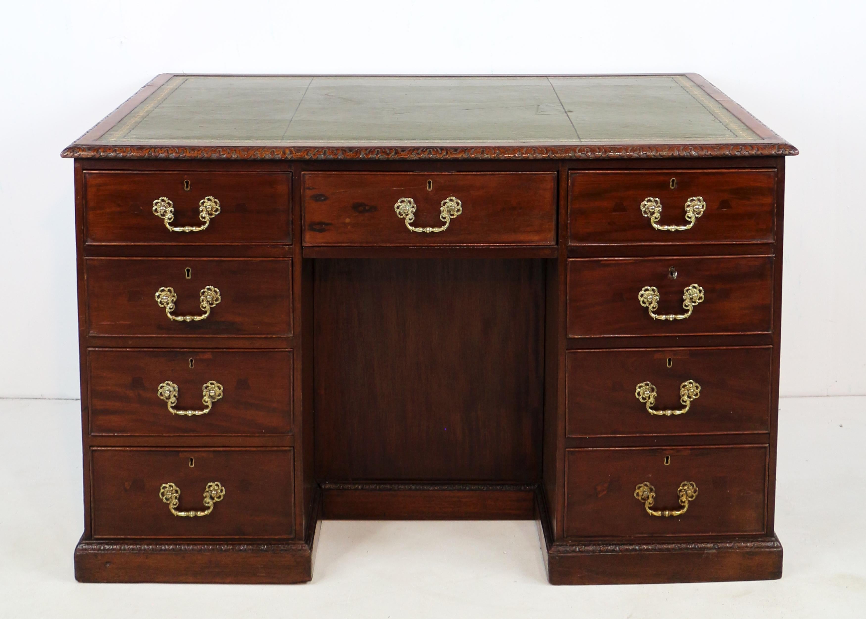 A George III mahogany freestanding library desk in the Chippendale style.  Designed to be used in the centre of a room and with storage to front and back similar to a partners’ desk, it has a gilt tooled green leather writing surface set within a