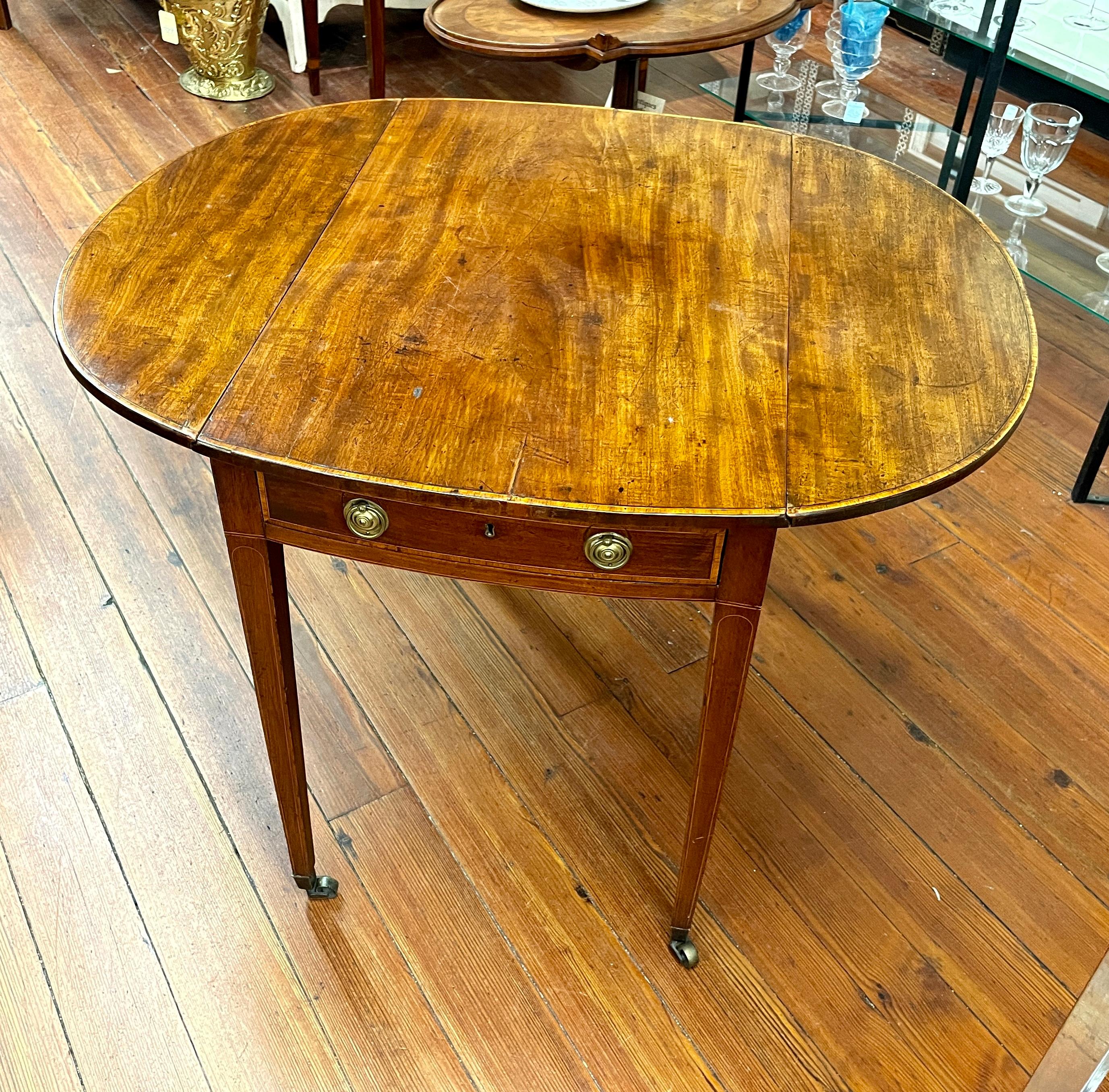 Fine antique English period George III inlaid mahogany oval drop-leaf Pembroke table. 
Please note: this item has original brasses intact, with lovely and delicate proportions, and wonderful patina and color. 
Table retains its original casters.