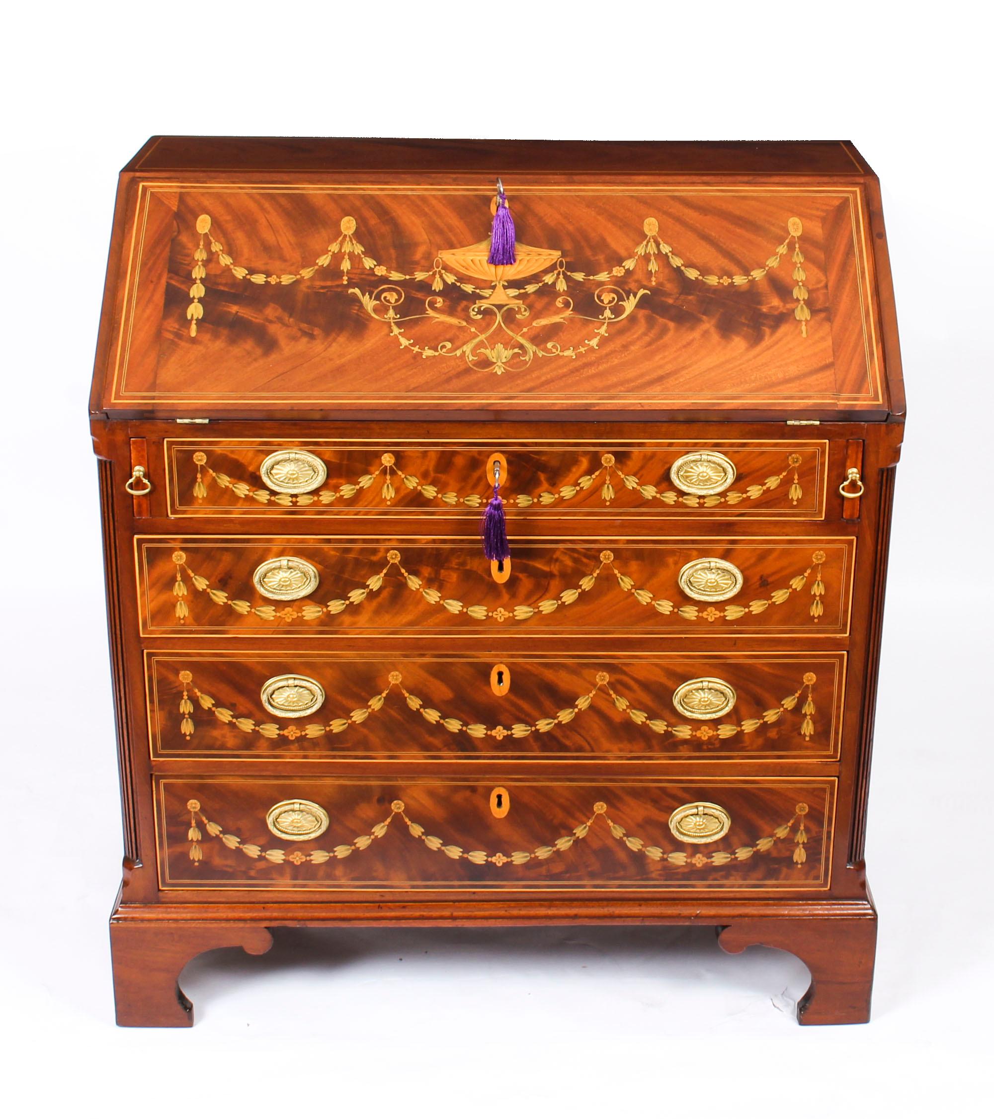 This antique bureau is late 18th century in date and has been beautifully crafted from top quality well figured flame mahogany which has been richly later inlaid with superb marquetry decoration comprising a large decorative urn and several garlands