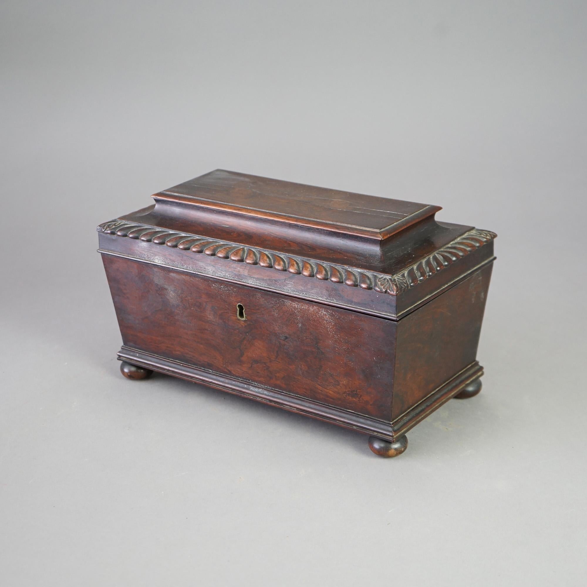 An antique English George III tea caddy offers rosewood construction in casket form with gadroon elements and raised on bun feet, c1820

Measures - 8