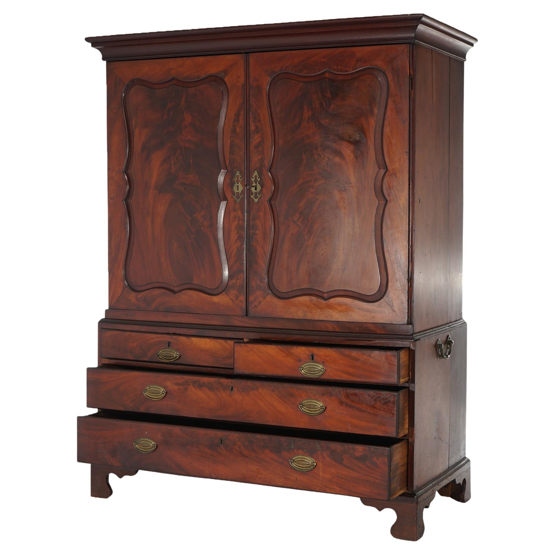 An antique English Georgian linen press offers flame mahogany construction with upper having paneled doors over lower case having two smaller drawers over two long drawers, raised on bracket feet, c1810

Measures - 67.75