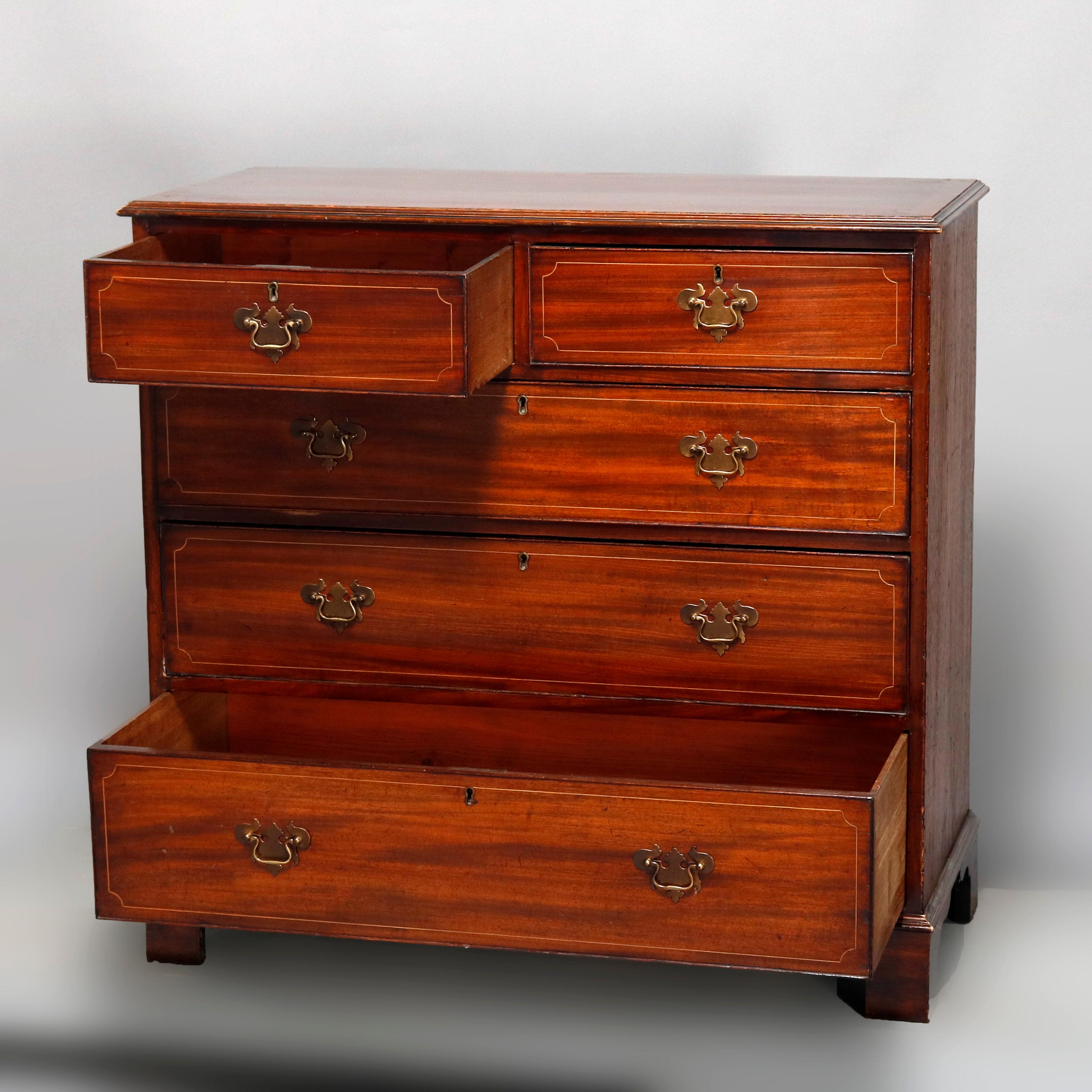 An antique English Georgian chest of drawers offers construction with deeply striated mahogany case having two smaller upper drawers over three long drawers, satinwood inlaid banding throughout and raised on bracket feet, 19th century

Measures: