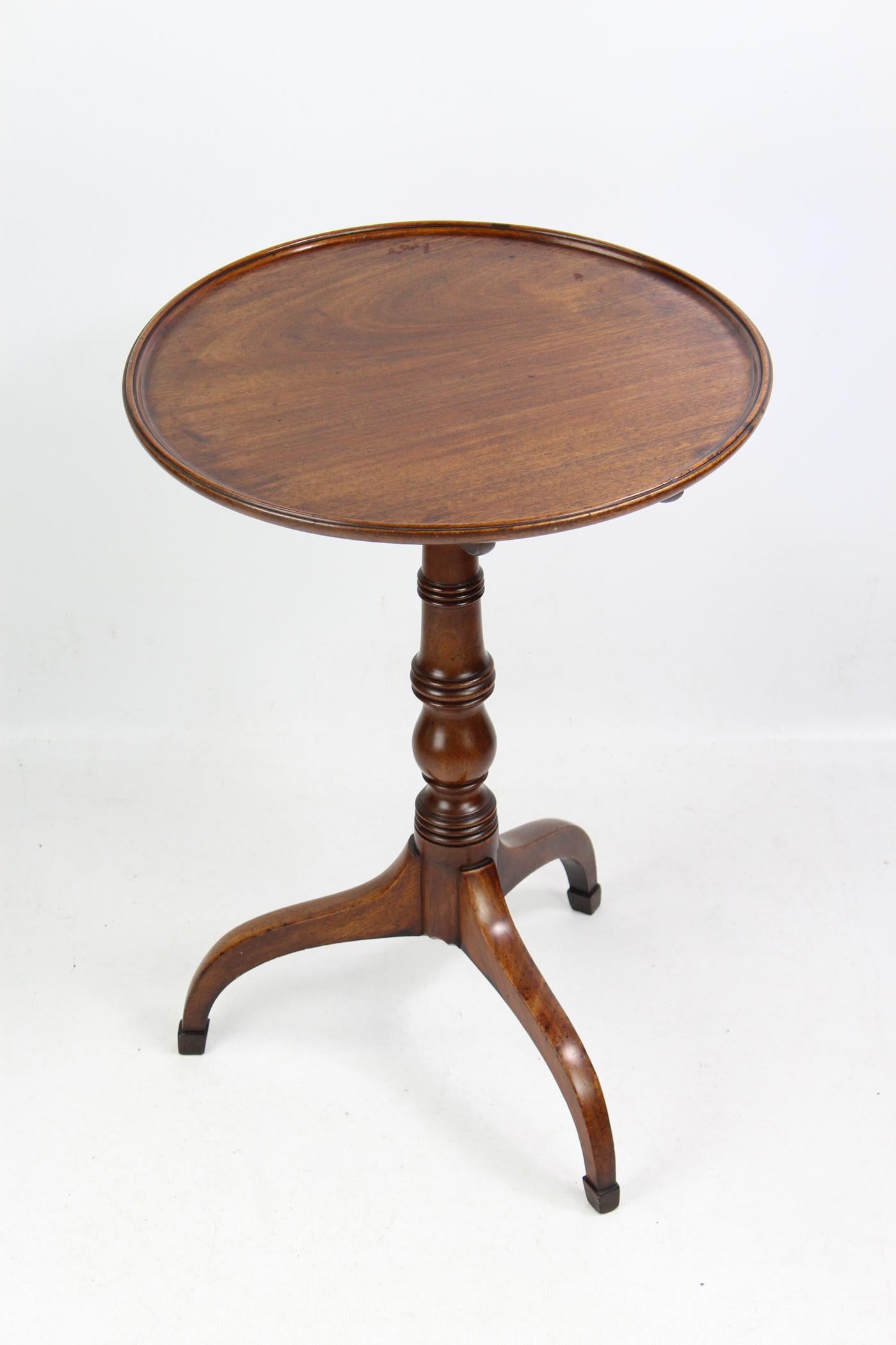 A superb antique Georgian mahogany tilt-top tripod wine table dating from circa 1800. With circular solid mahogany tilting top with raised and moulded edge supported by a crisply turned central column supported by shaped tripod legs with pointed