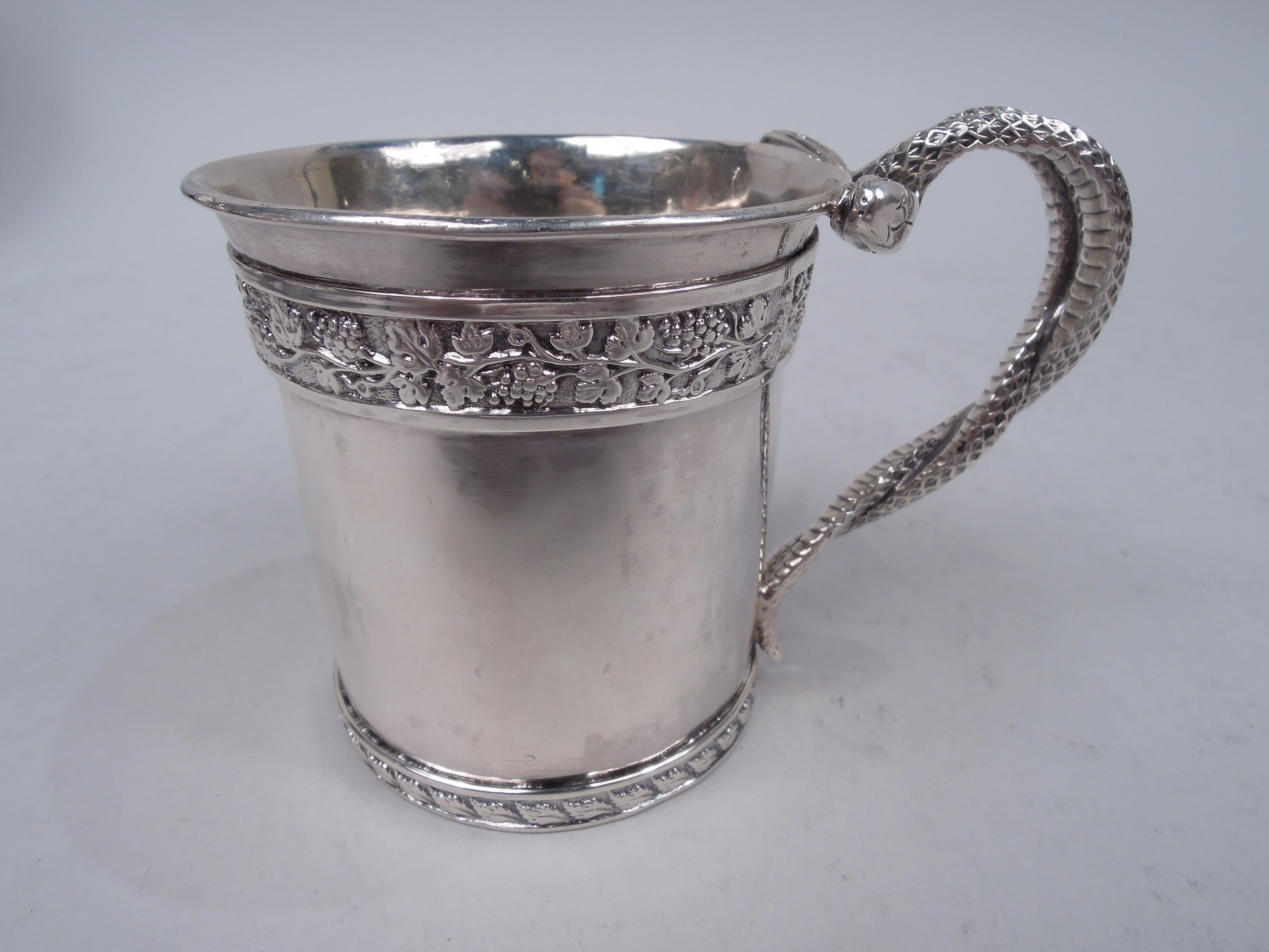 George III sterling silver baby cup. Made by William Bennett in London 1811. Flared rim with low-relief fruiting grapevine border; leaf border at bottom. Cast handle in form of two snakes with entwined scaly bodies and bead-eyed heads. Gilt-washed