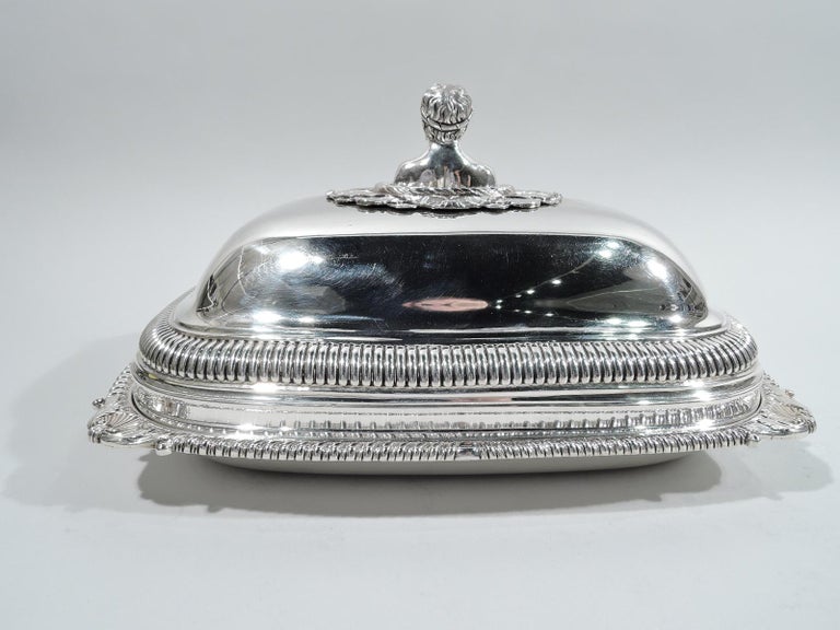 George III sterling silver covered serving dish. Made by Thomas Robins London in 1814. Rectangular with gently curved sides. Rim gadrooned with corner shell-and-leaf ornament. Cover double-domed with gadrooning. Central cast finial in form of