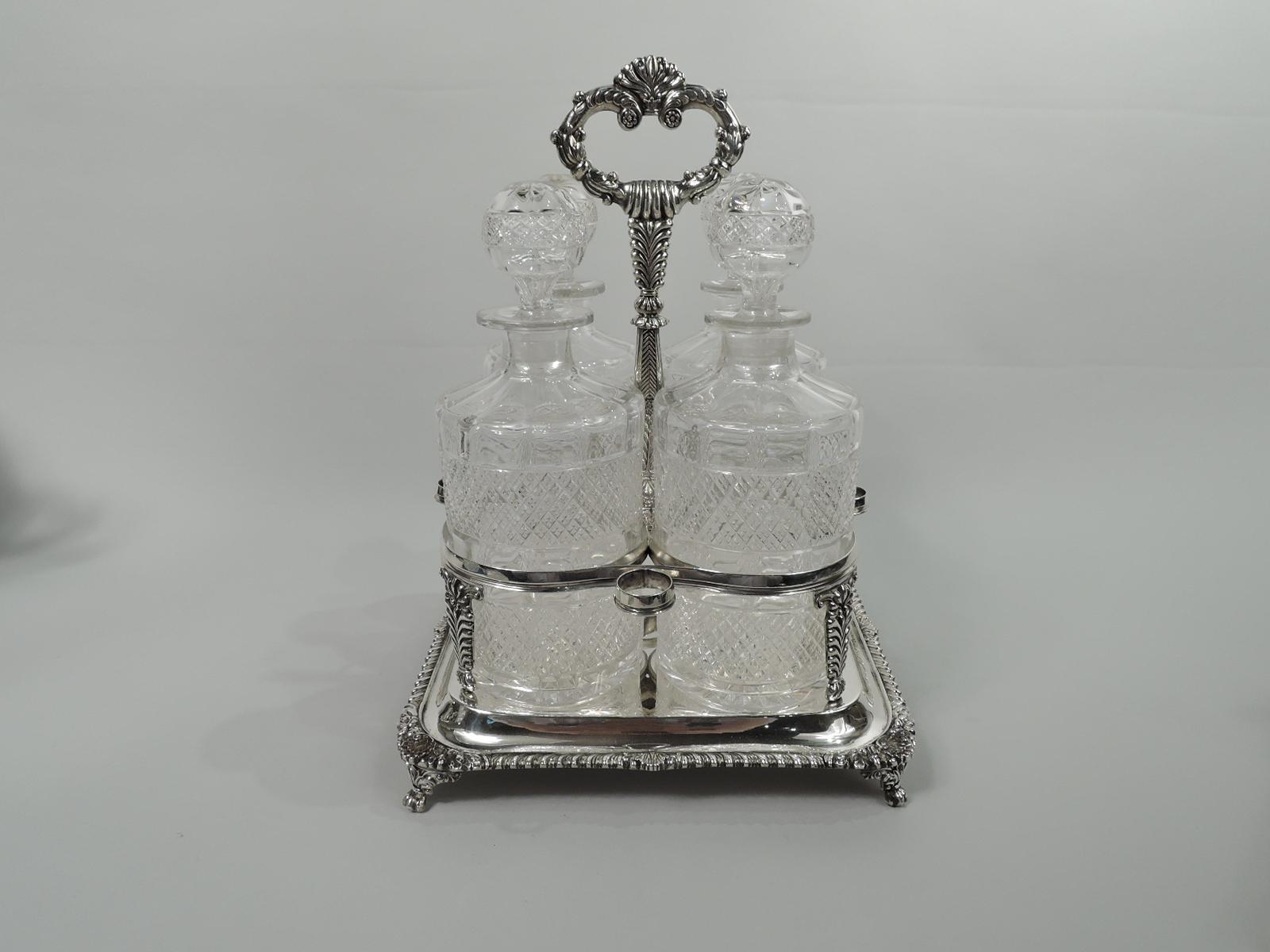 English Georgian neoclassical sterling silver decanter stand, 1818. Raised square base with gadrooned rim. Corner shells between oak leaves and acorns on leaf- and scroll-mounted paw supports. Four bottle and 4 stopper rings on imbricated leaf
