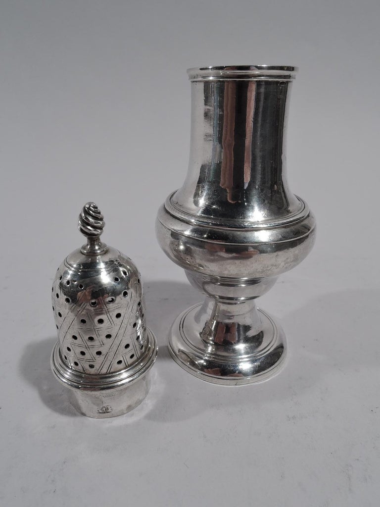 English Georgian sterling silver condiment shaker, late 18th century. Baluster on raised foot. Cover pierced with engraved diaper and twisted finial. Worn marks include crowned T (body) and crowned V and letters RP (cover). Weight: 2.8 troy ounces.