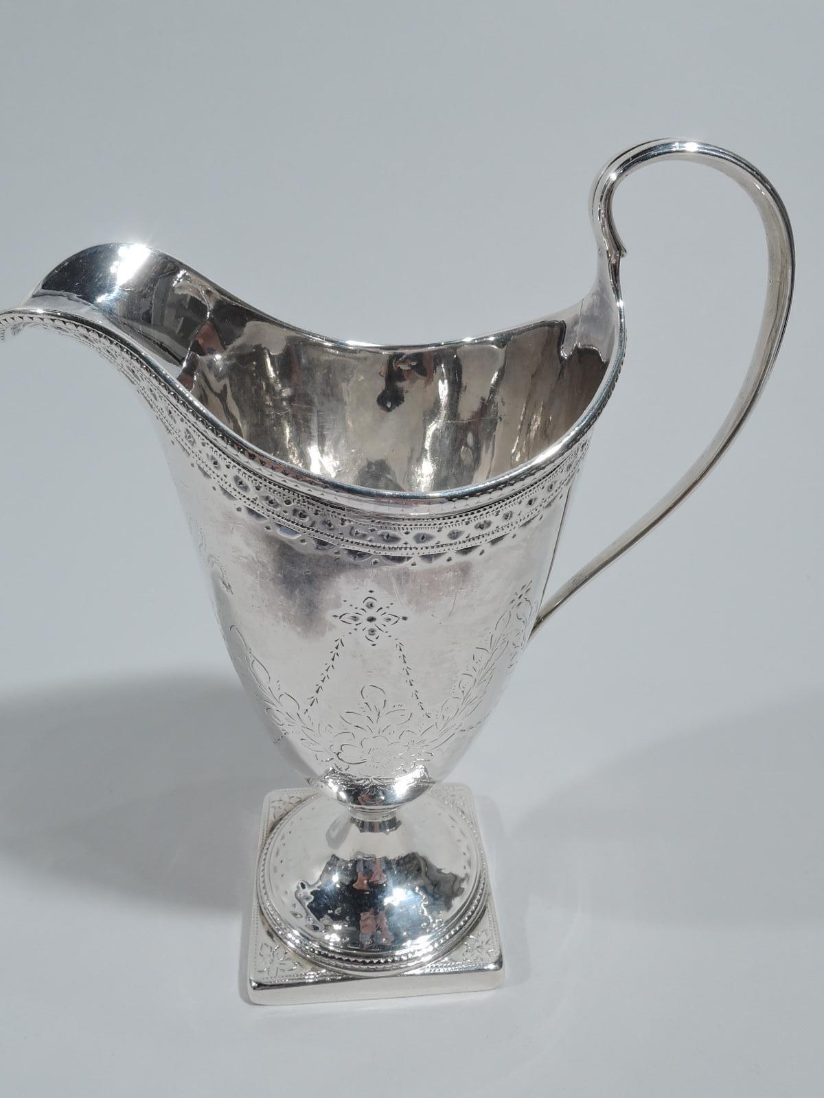 English Georgian neoclassical sterling silver creamer, 1786. Tall ovoid bowl with high-looping handle and helmet mouth; raised foot mounted to square base. Engraved pendant flowers and wreath cartouche (vacant). Fully marked including London assay