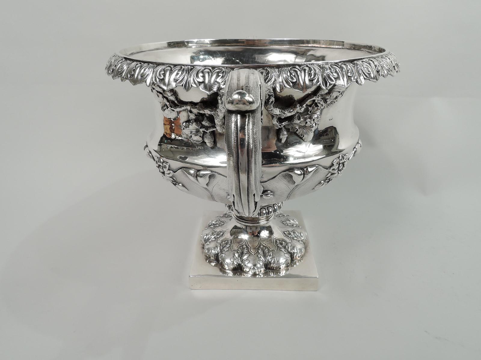 English Georgian Regency sterling silver bowl. Made by Rebecca Emes and Edward Barnard in London, ca 1830. Bellied bowl with chased and stippled leaf and flower bowl. Concave neck and turned-down leaf-and-dart rim. Leaf-capped and -wrapped side