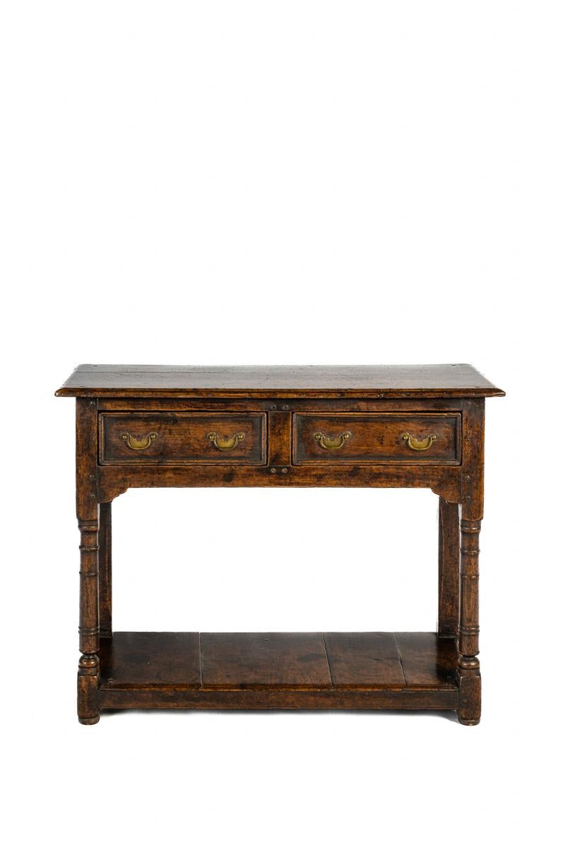 This stunning antique English Georgian console table or sideboard was crafted in the mid-19th century, around 1850. The exterior of the sideboard is made entirely of beautiful European summer oak. The table features two front drawers, each measuring