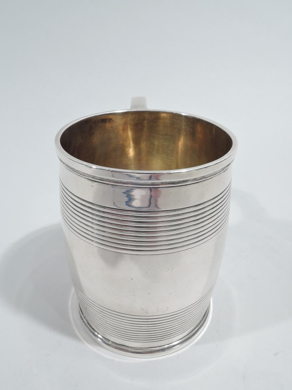 English Georgian sterling silver baby cup, 1822. Barrel body with reeded bands and scroll bracket handle. Interior gilt washed. A historic mug with room for engraving. Fully marked including London assay stamp, George IV duty stamp, and worn maker’s