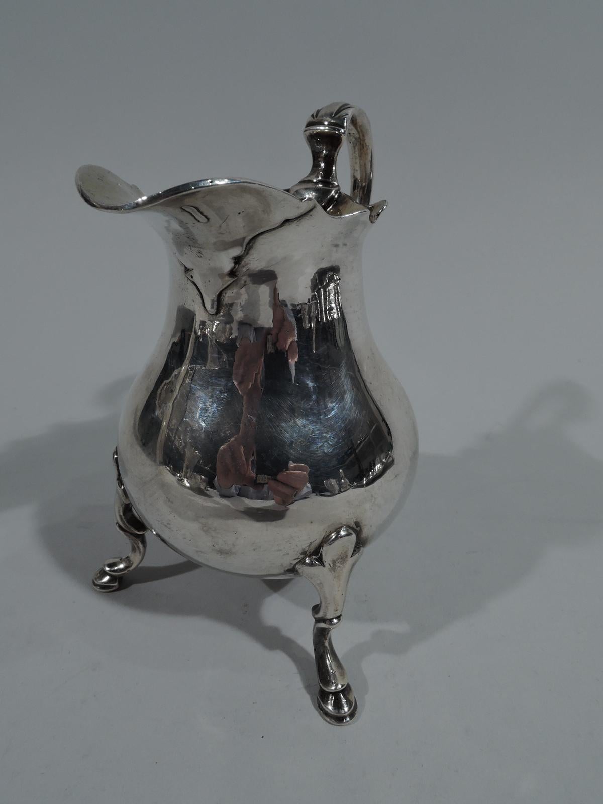 George II sterling silver creamer. Made in London in 1743. Baluster with scalloped helmet mouth, irregular leafy-spout, leaf-capped double-scroll handle, and 3 trefoil-mounted scrolled hoof supports. Interior gilt-washed. Beautiful Georgian with