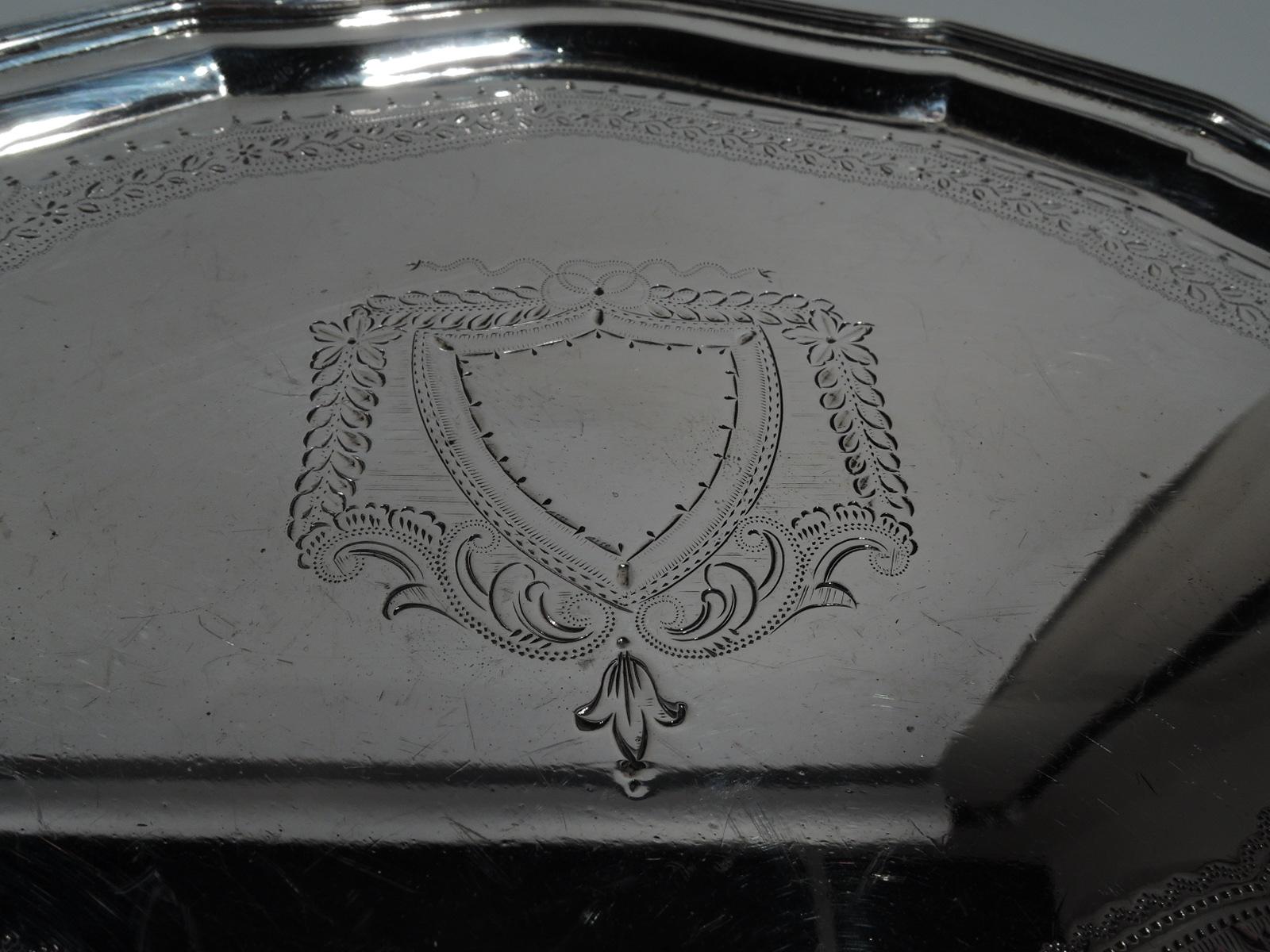 George V sterling silver salver. Made by Ellis Jacob Greenberg in Birmingham in 1923. Curvilinear cartouche with molded rim on 4 triangular supports. Engraved armorial (vacant) and ornamental border. Hallmarked. Weight: 6 troy ounces.