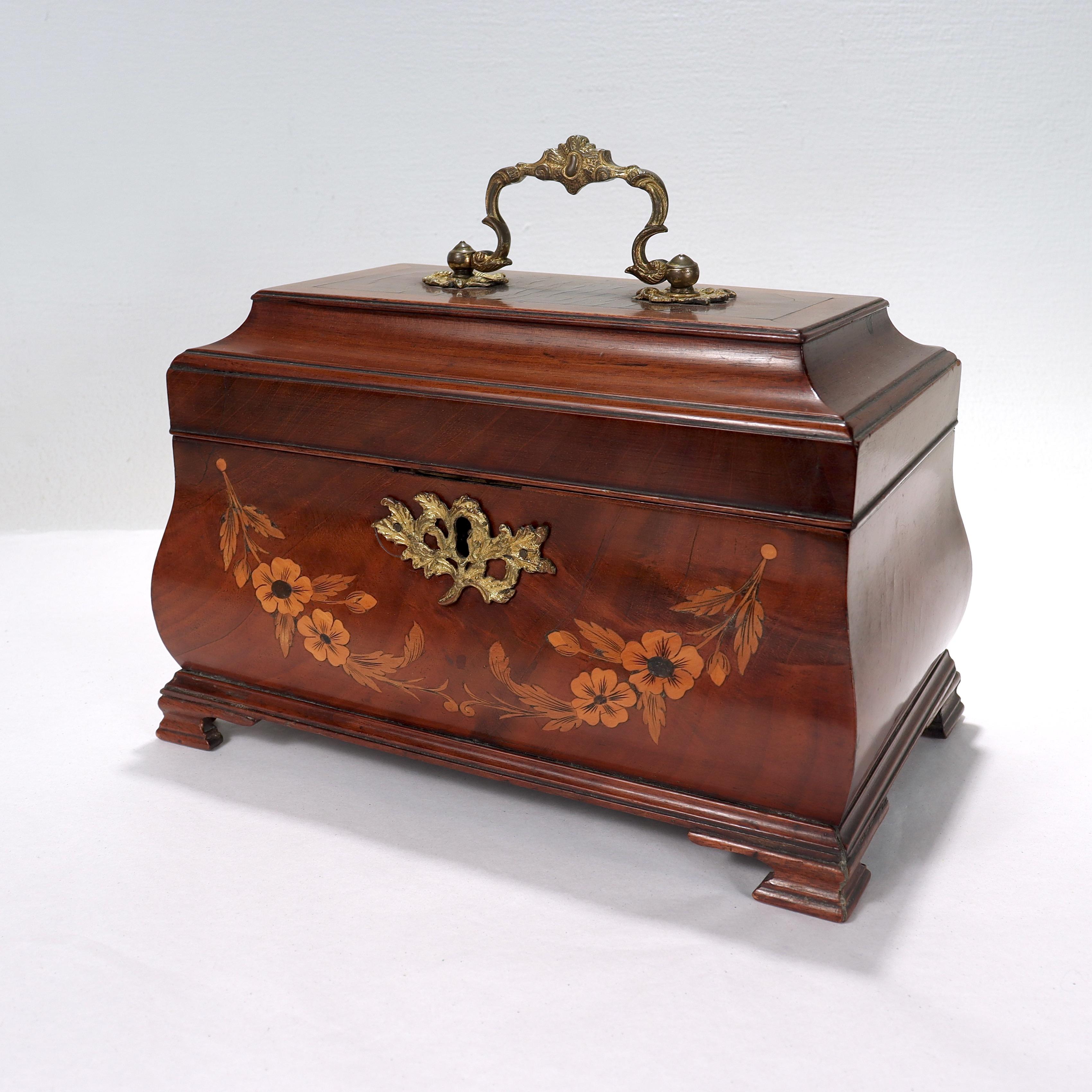 A fine antique Georgian style mahogany tea caddy. 

Of bombé form with fruit wood inlay, gilt brass mounts & handle, and bracket feet.

Simply a wonderful, rare form!

Date:
Late 19th or Early 20th Century

Overall Condition:
It is in