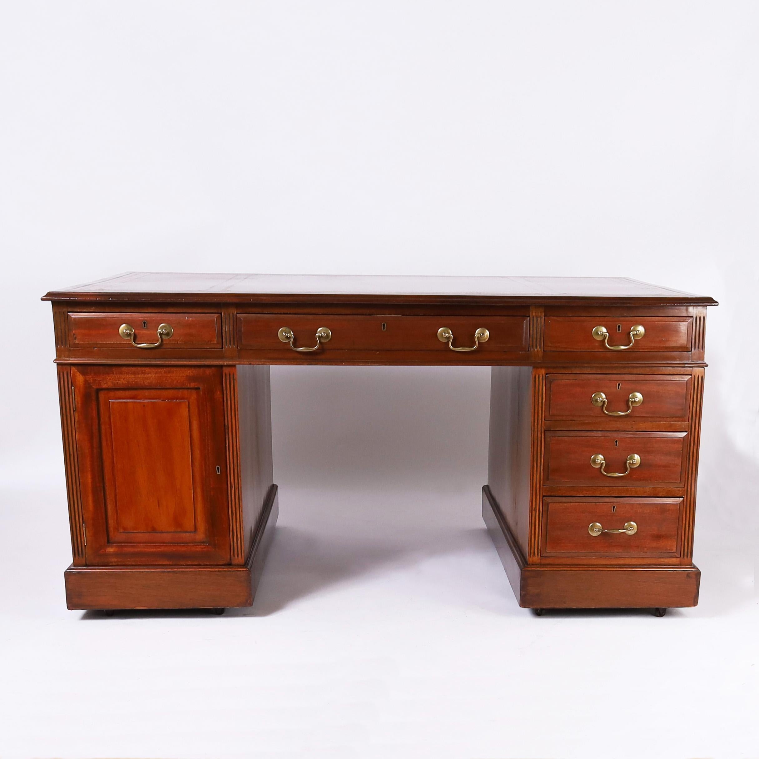Bellissima scrivania per partner in stile British Colonial del XIX secolo, realizzata a mano in mogano e composta da tre pezzi con un piano in pelle lavorata, sei cassetti e un armadietto sul davanti e lo stesso sul retro, ferramenta in ottone e