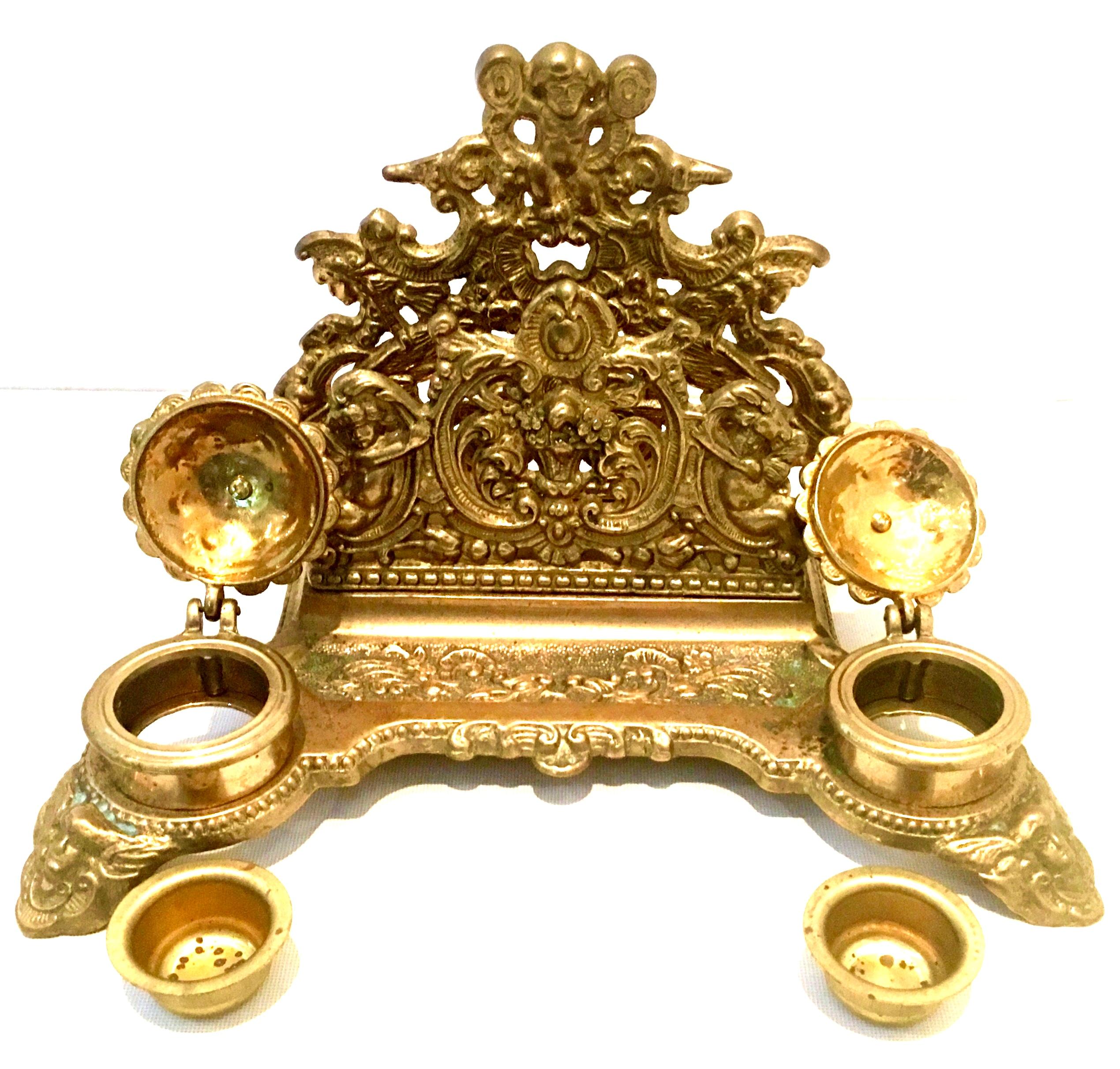 Antique English gilt gold brass letter holder and double inkwell desk set. Finely crafted of carved and etched gold gilt solid brass with intricate and high relief motif of scrolls, floral, foliate and putti. Footed with a pen tray and pierced cast