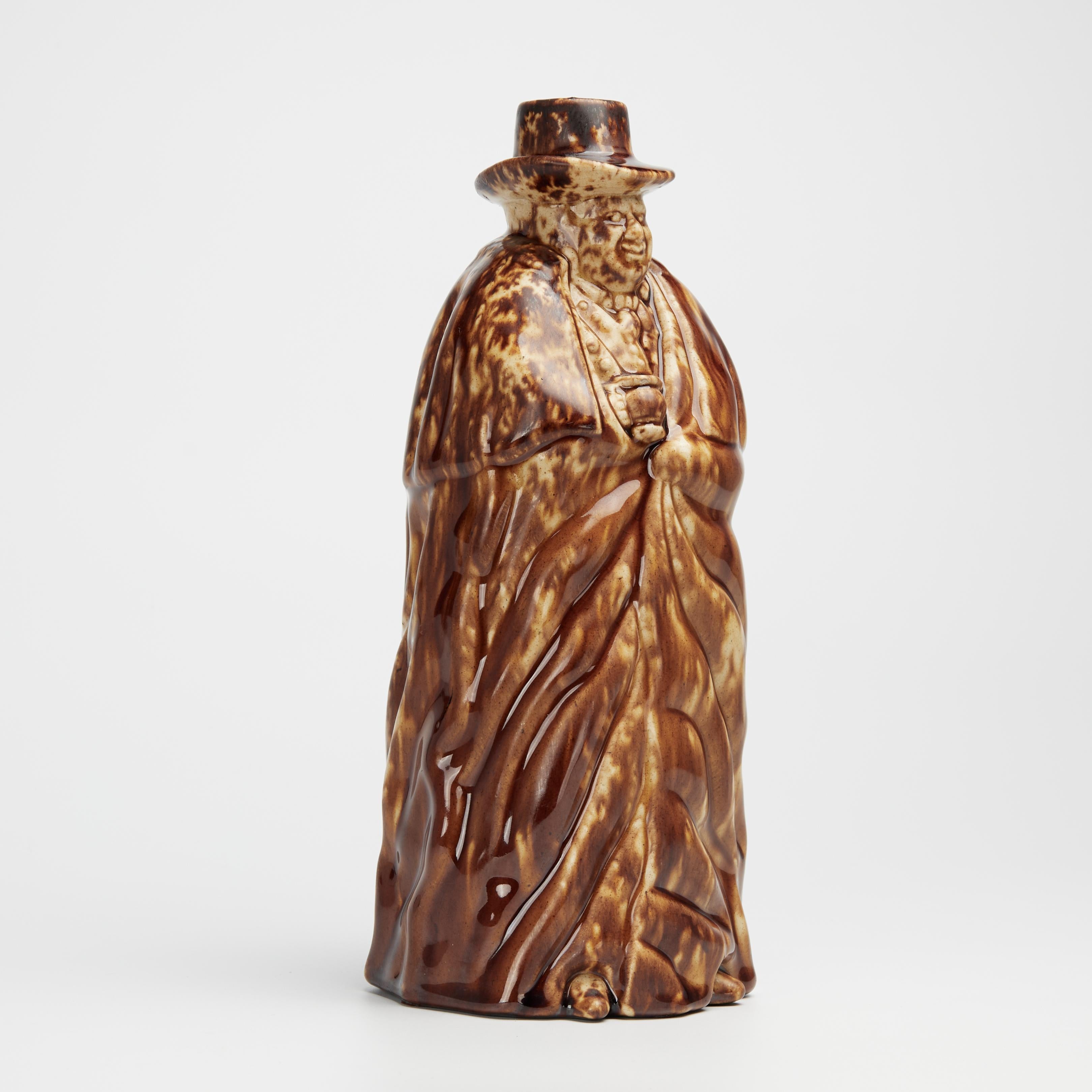 Intrigante botella inglesa del siglo XIX hecha a mano en terracota con forma de cochero con sombrero y capa y acabada con un grueso vidriado. Firmado en la parte inferior Lyman, Fenton & Co. Rockingham.