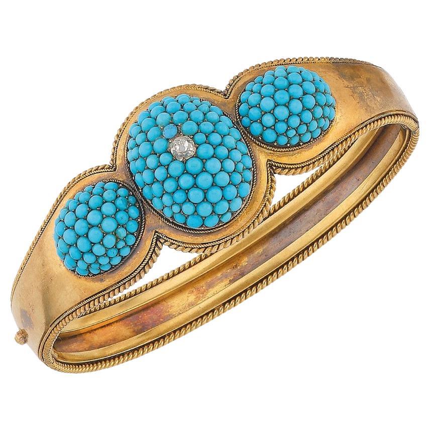 Rigid, articulated cuff-type bracelet in yellow gold,set with three pave’ turquoise topped by an old cut diamond in a filigree setting. English work, circa 1870's.  Total gross weight: 28,30gr;  Diam. 5.6 cm
In original case.