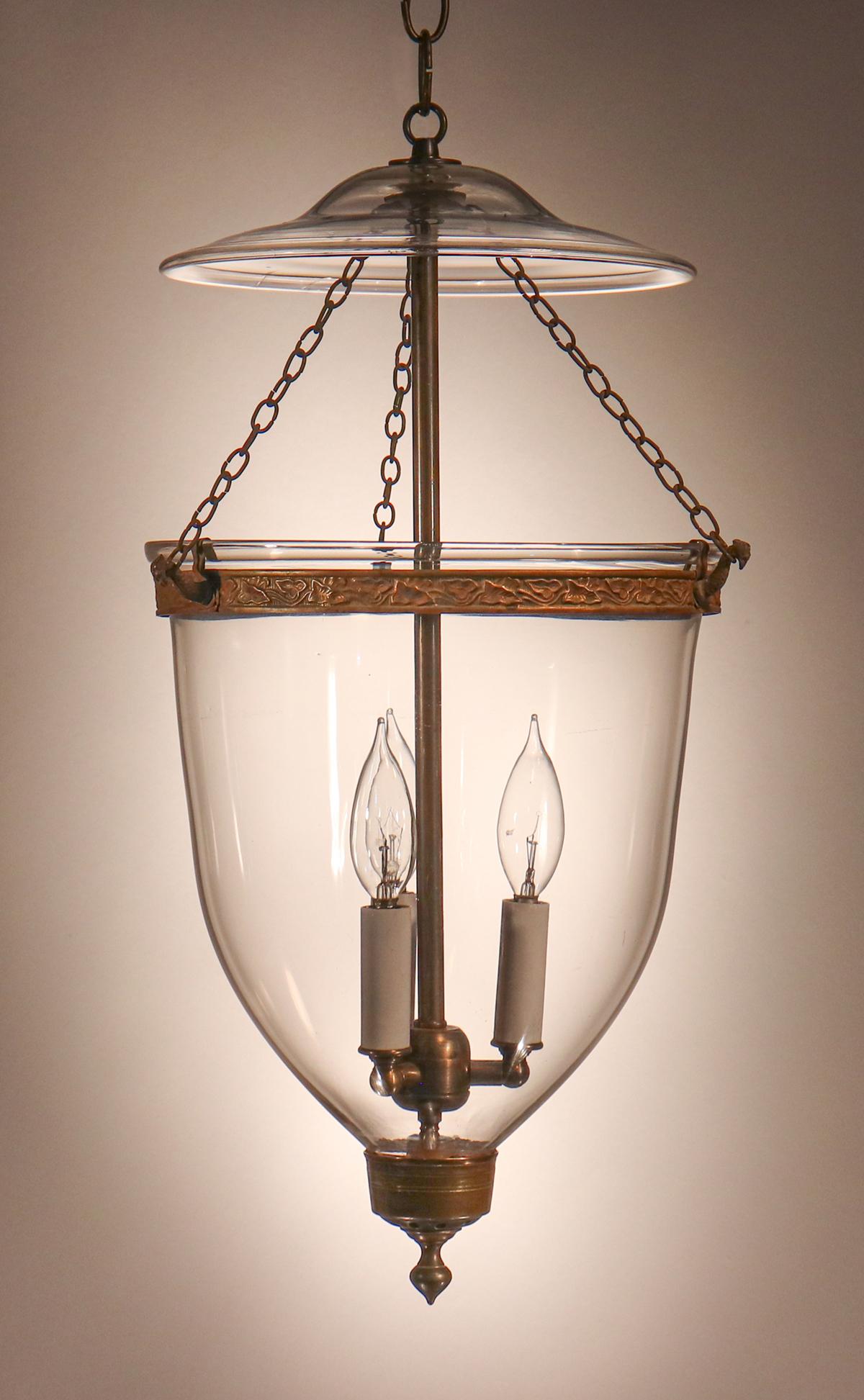 A beautiful, classic English bell jar lantern with clear hand blown glass. This circa 1850 lantern features an original embossed band and teardrop finial/candleholder base. It has been newly electrified with a three-bulb candelabra cluster. The