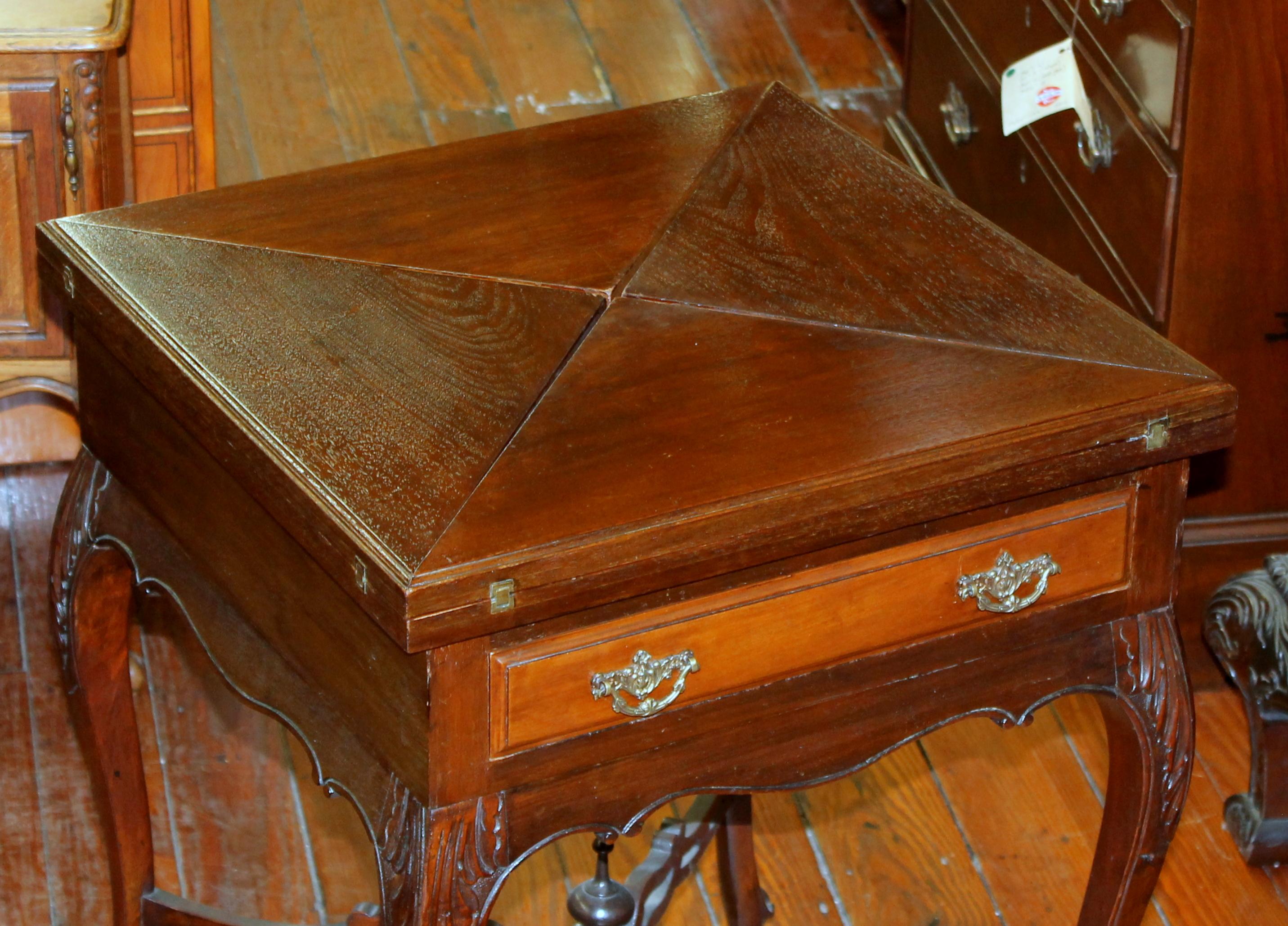 Fine quality antique English hand carved walnut French style envelope folding games table with tooled leather surface; original brass handles and casters. Please note finely carved attributes as well as the pierced stretcher beneath. (As you turn