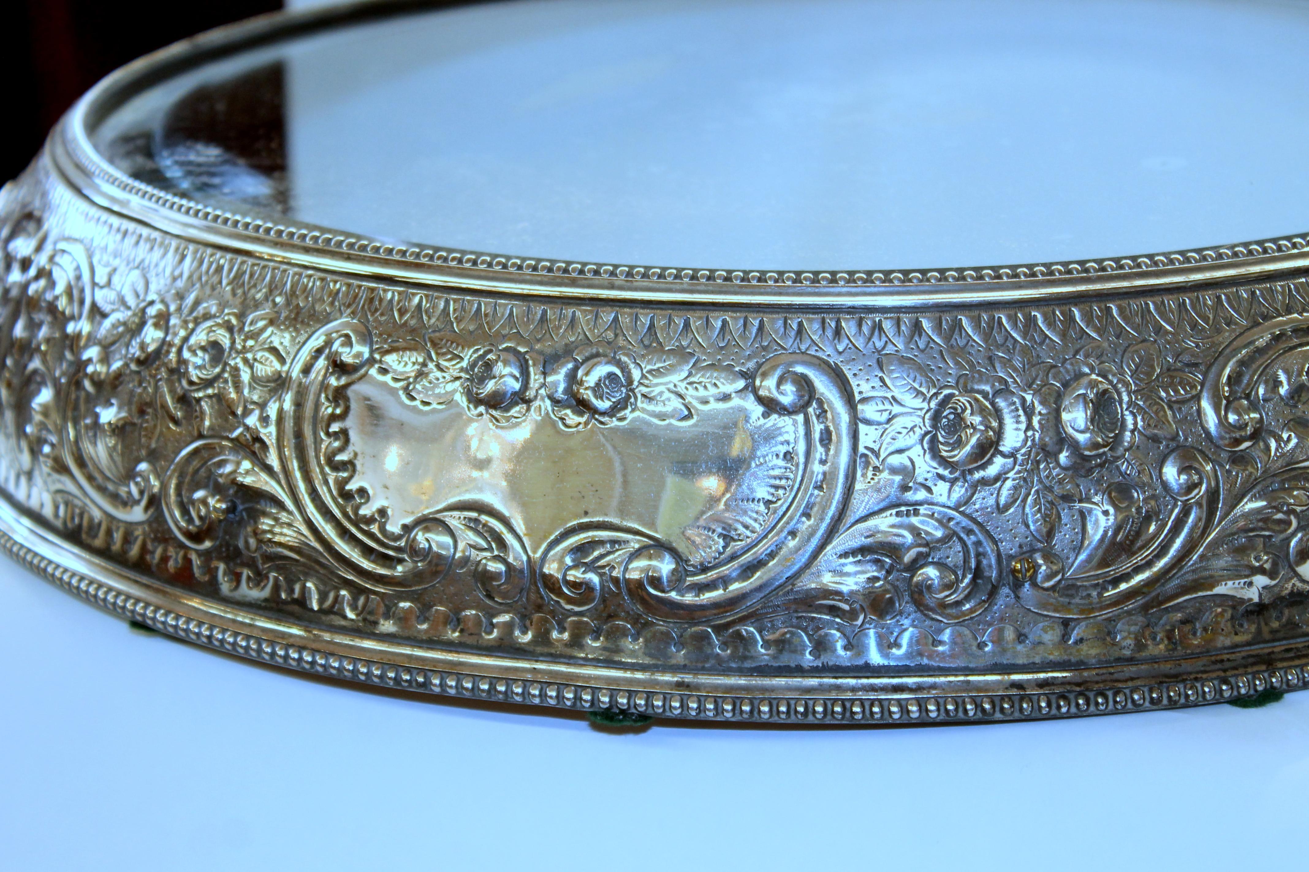 Magnificent antique English hand chased silver plate large, round mirror plateau.  

Unusually large size with exceptional hand chased border; original beveled mirrored glass (some spots beneath the mirrored glass noted); some minor plate loss