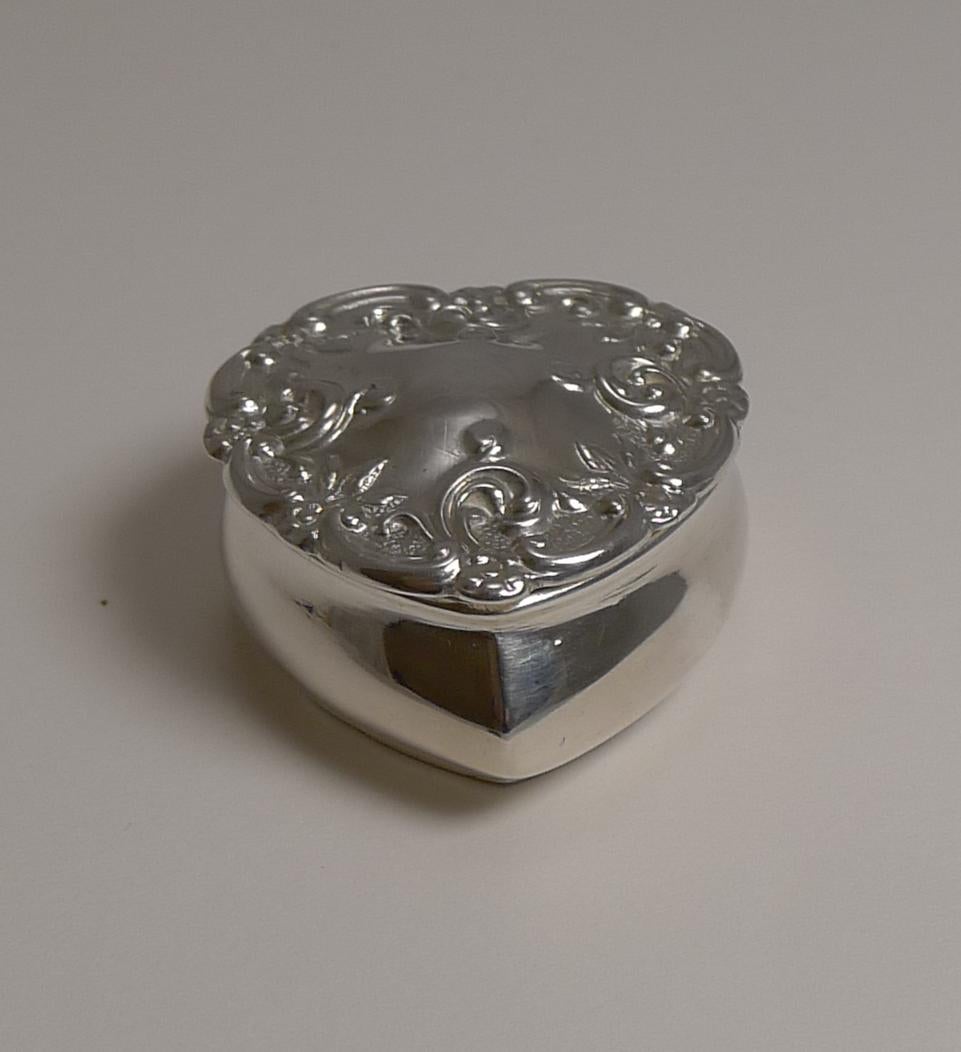 A charming and very romantic heart shaped pill box made from English sterling silver and dating to the Edwardian era.

The hinged lid fits well with it's domed lid and pretty repousse decoration with a vacant cartouche to the centre. The interior is