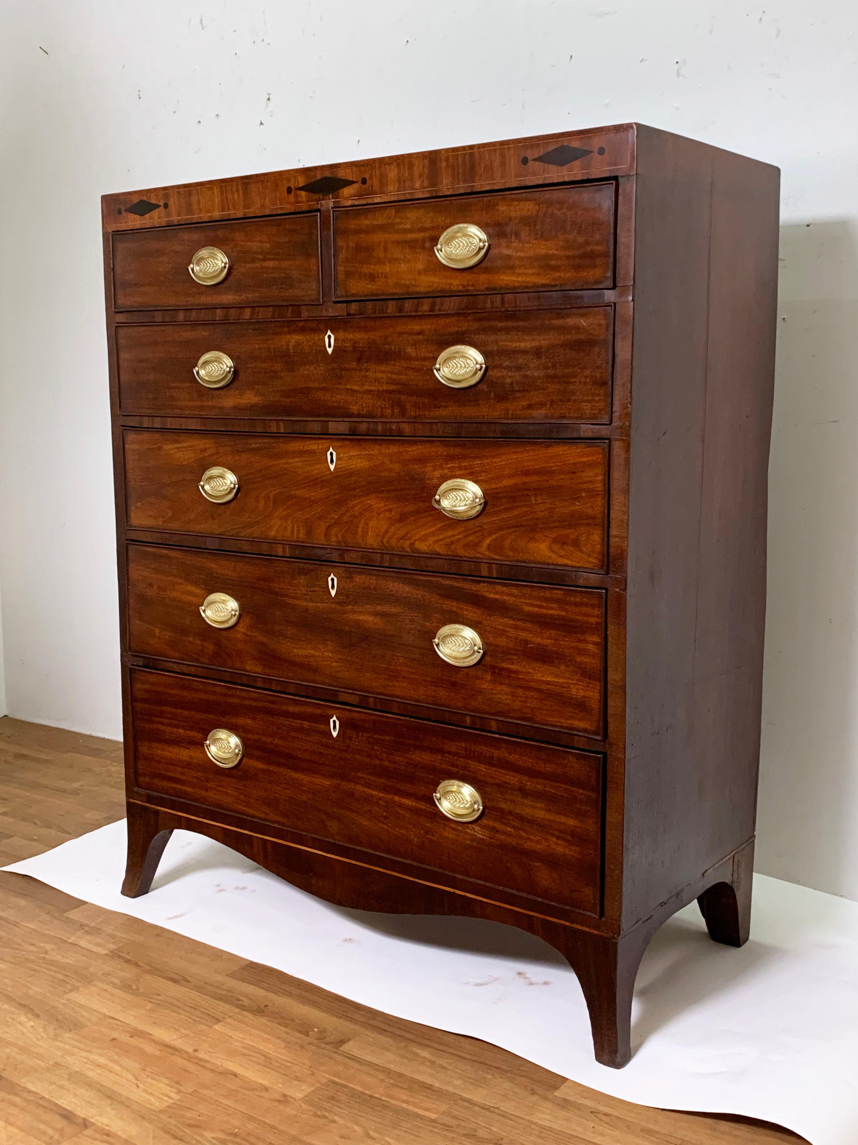 An English Hepplewhite chest of two drawers over four graduated drawers in walnut with serpentine skirt and ebony inlaid crosshead. This period chest features several drawers lined with page from The York Herald newspaper dated 1818.