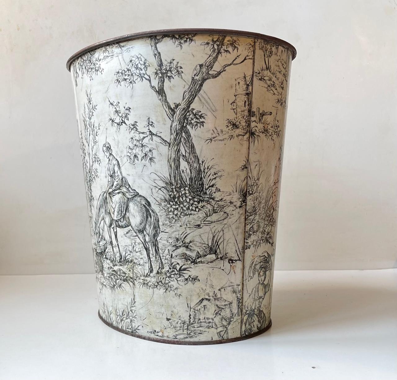 A rare surviver in the shape of this oval litter trash can for paper and office 'left-overs'. Its made from transfer-printed tin-plate featuring a micro-cosmos of idyllic scenes. It was made in England during the 1920s or 30s. Measurements: H: 30