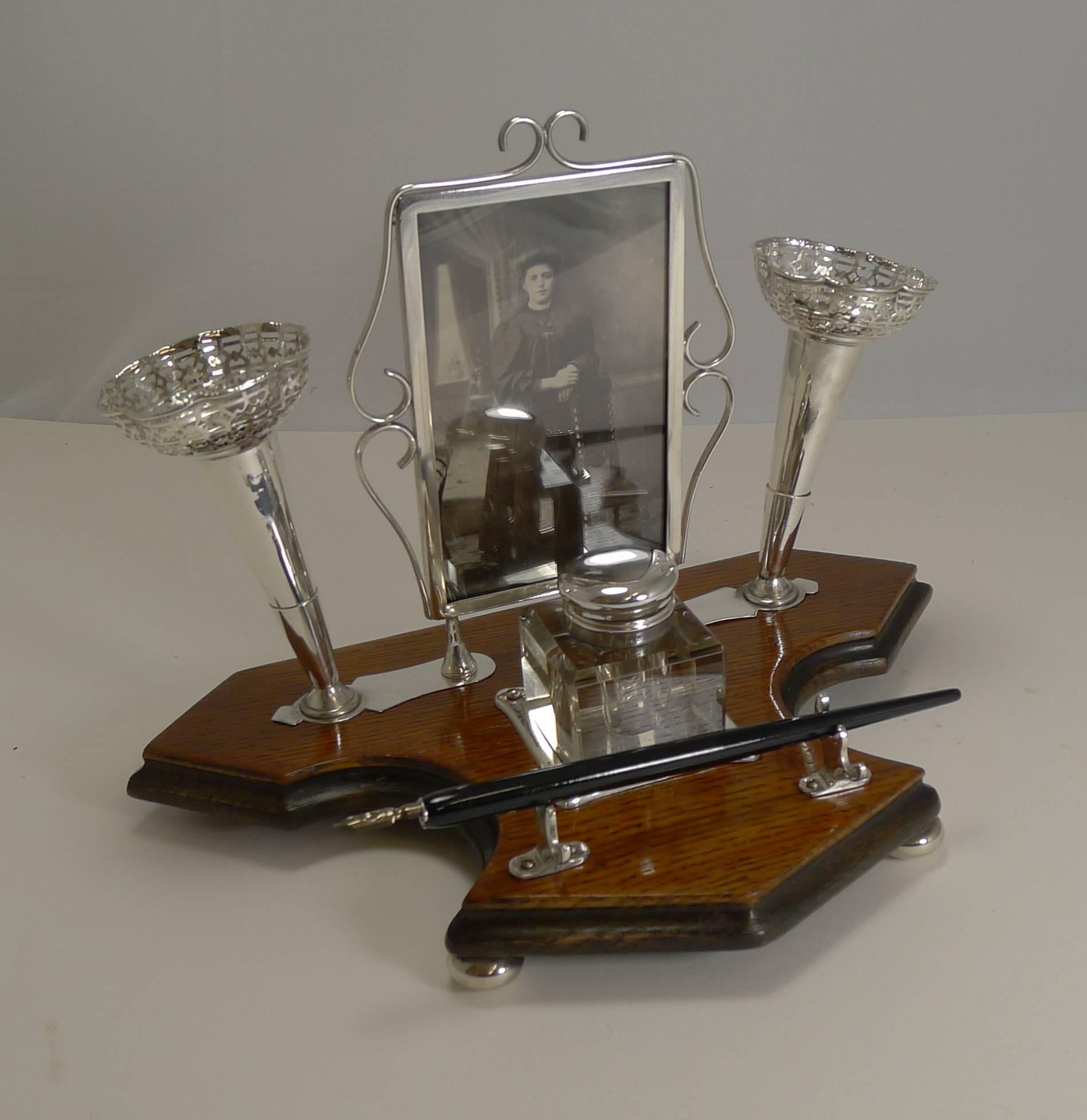 A truly unusual desk set made from a winning combination of solid English oak contrasted with the bright silver plated fittings.

Standing on four original bun feet, the base is made from oak with an ebonized edge.

Of course what makes this an