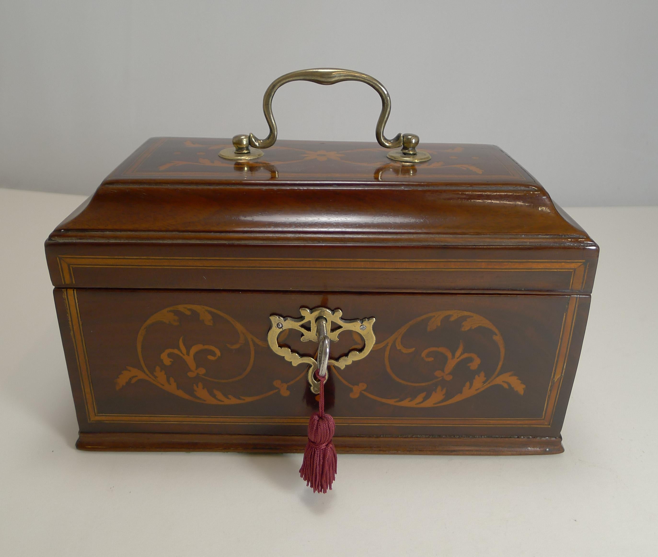 A very handsome George III tea caddy, made from Mahogany and beautifully inlaid with panels and highly decorative foliate marquetry to the front and top. The top has a handsome cast brass handle with a complimentary cast brass escutcheon which