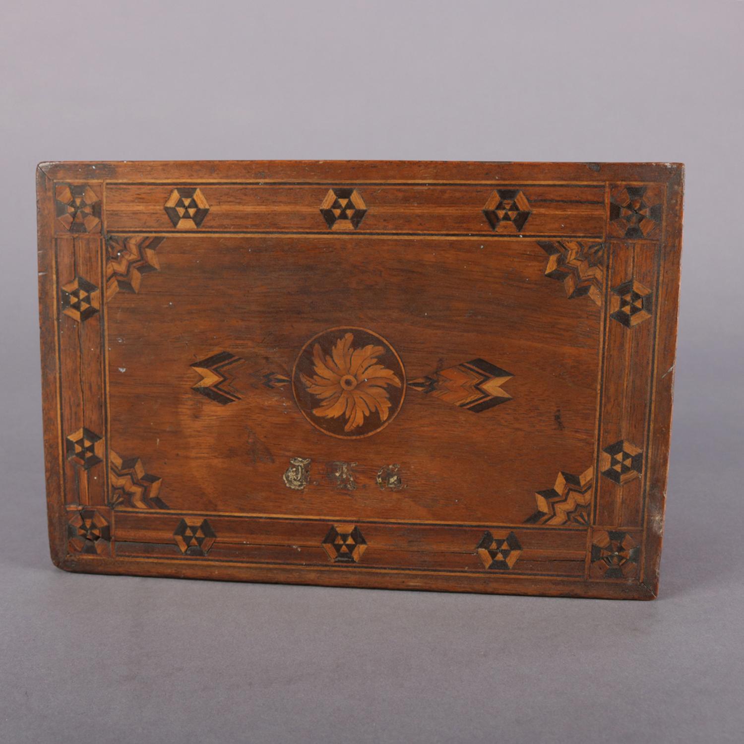 Antique English parquetry petite humidor features two toned inlay throughout including banding, central acanthus pinwheel medallion and chevron sunburst corners, handles, lined interior, and monogrammed top, 19th century

Measures: 4.5