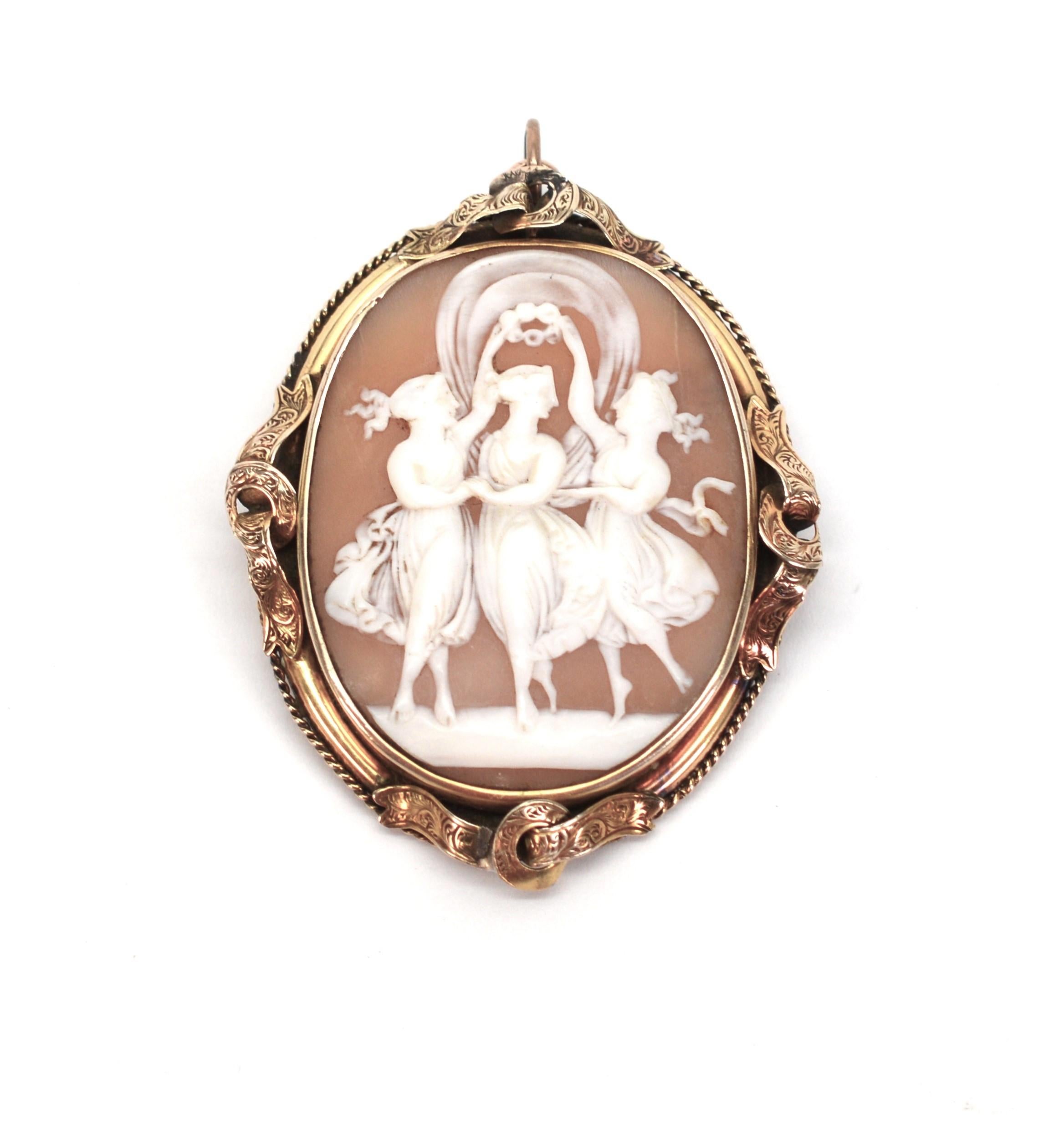 Magnificent hand-carved shell antique cameo brooch pendant featuring a the artist's depiction of the Three Graces framed  in an elaborate 9 karat yellow gold frame.  Victorian period, this romantic piece is inspired by the mythical 