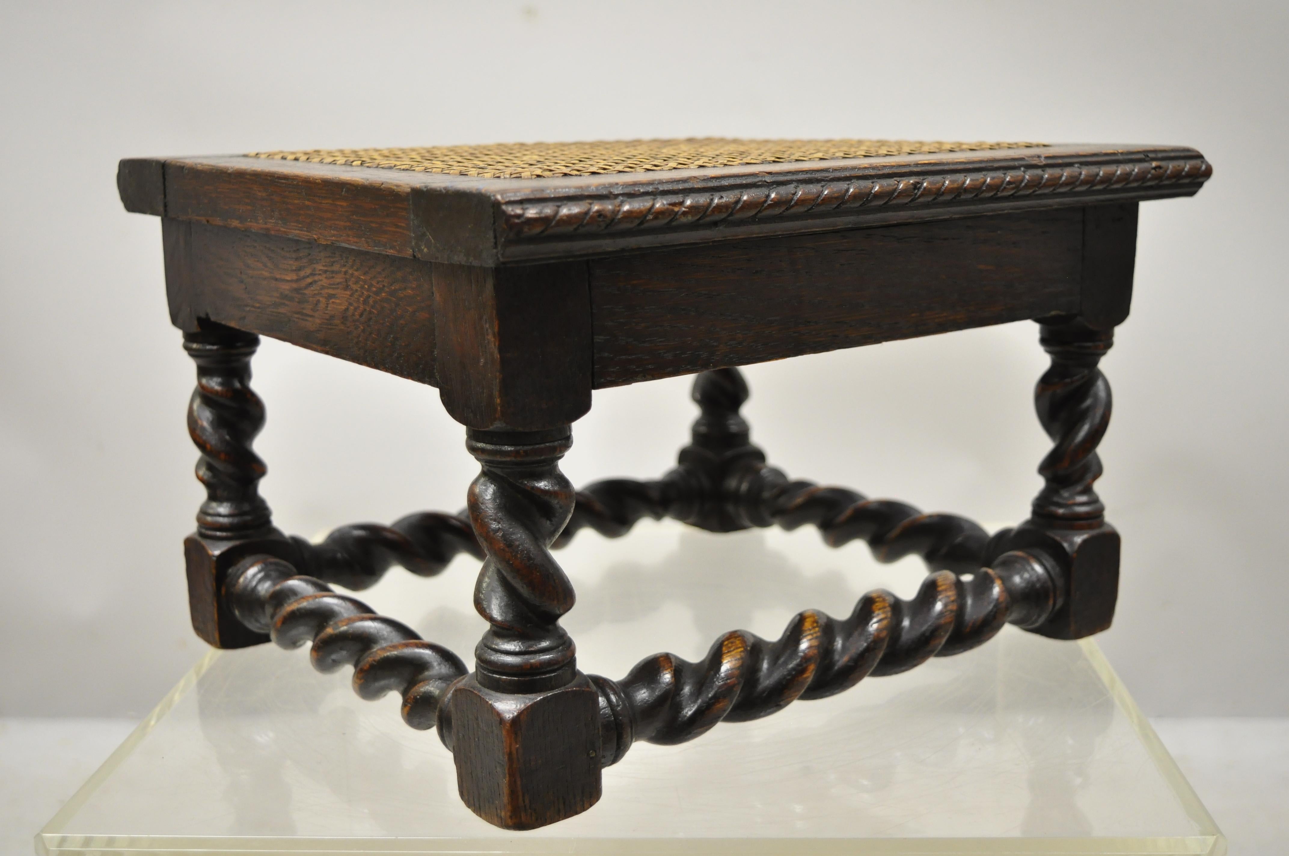 Antique English Jacobean Carved barley twist small footstool ottoman with cane seat. Item features a cane seat, remarkable patina, barley twist carved legs and stretcher, solid wood construction, beautiful wood grain, nicely carved details, very