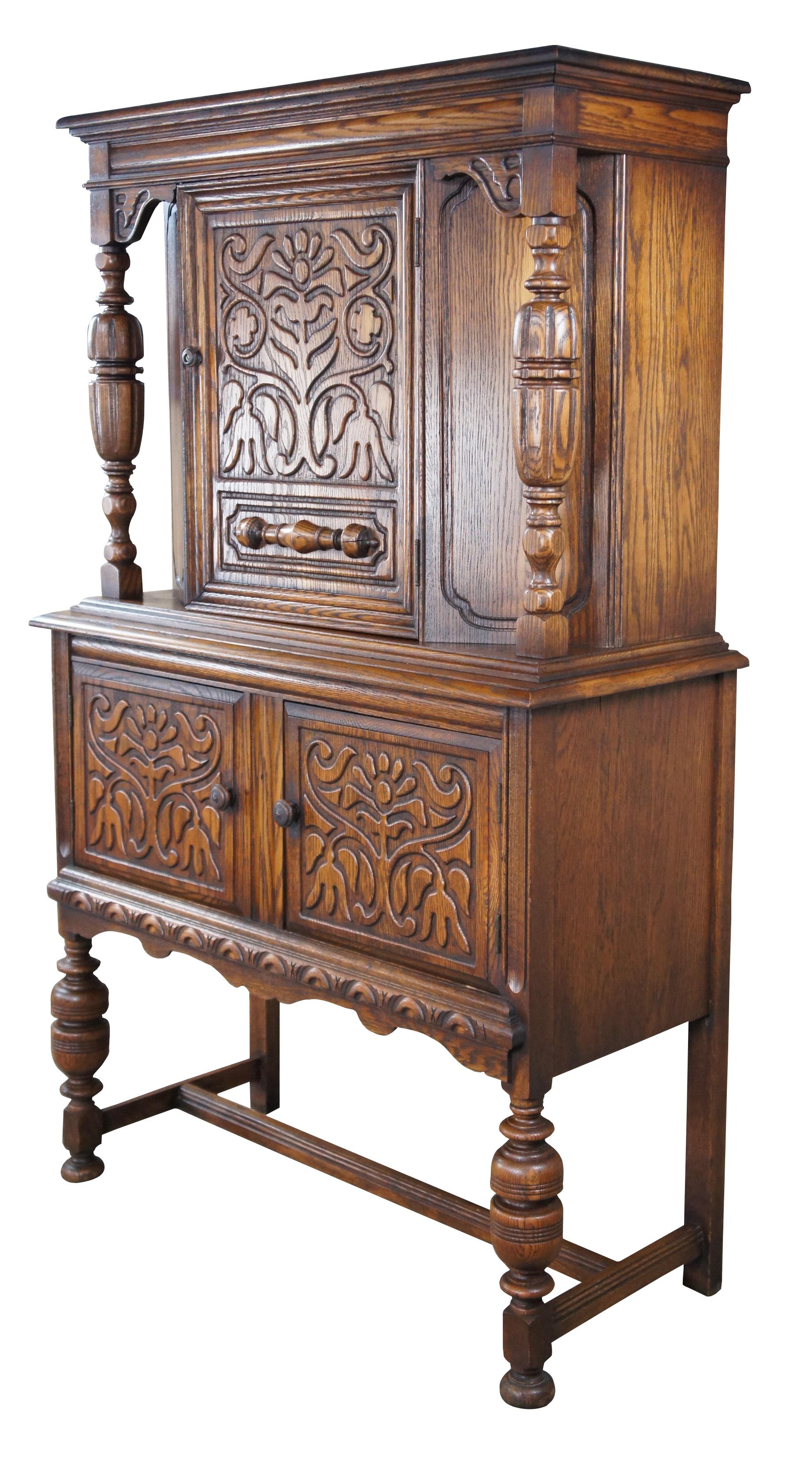 Early 20th Century Jacobean / Elizabethan revival court cupboard. Made from oak with an upper hutch mounted between two beautifully turned baluster supports. Features low relief foliate carved doors and a large lower storage area. The rectangular