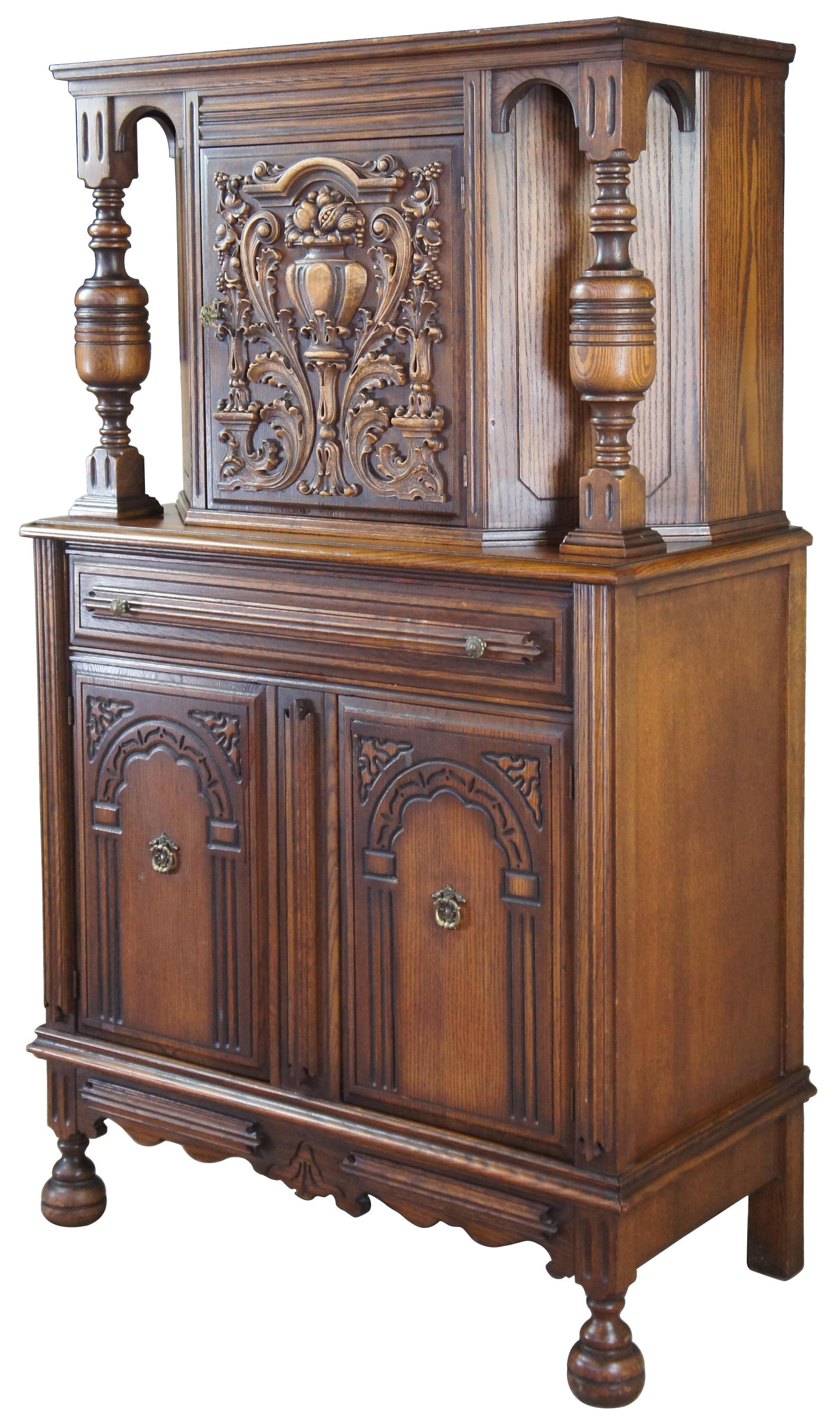 Early 20th century Jacobean / Elizabethan revival court cupbourd by Basic Furniture Company out of Waynesboro, Virginia. Made from oak with an upper hutch mounted between two beautifully turned baluster supports. Features a low relief carved door