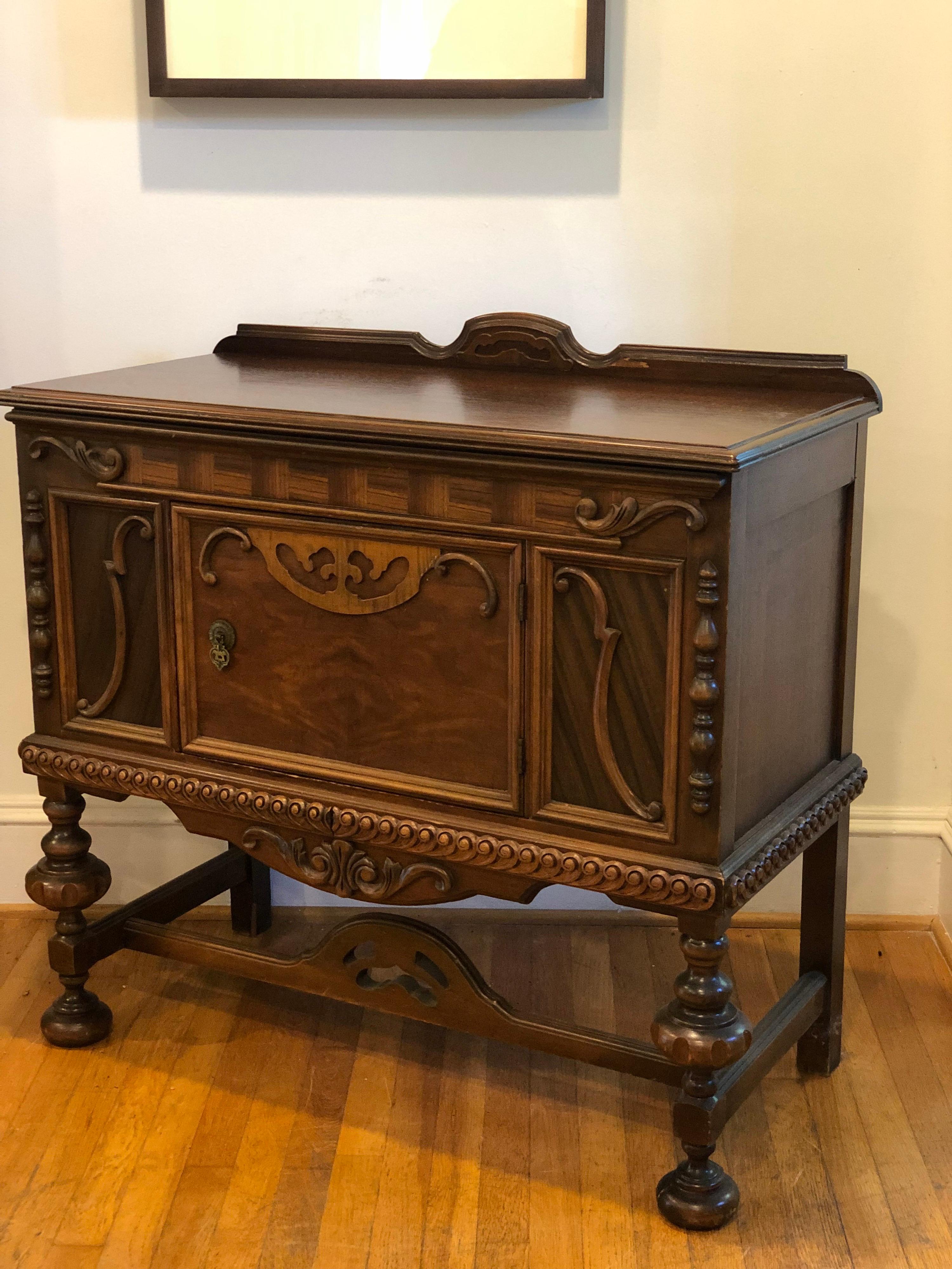 Early Jacobean/Elizabethan/Georgian revival buffet or sideboard.
Cabinet has one solid door with lots of storage for dishes, etc. 
Carvings in the doors and turned baluster legs.
Measures approx 39” x 18 x 34.