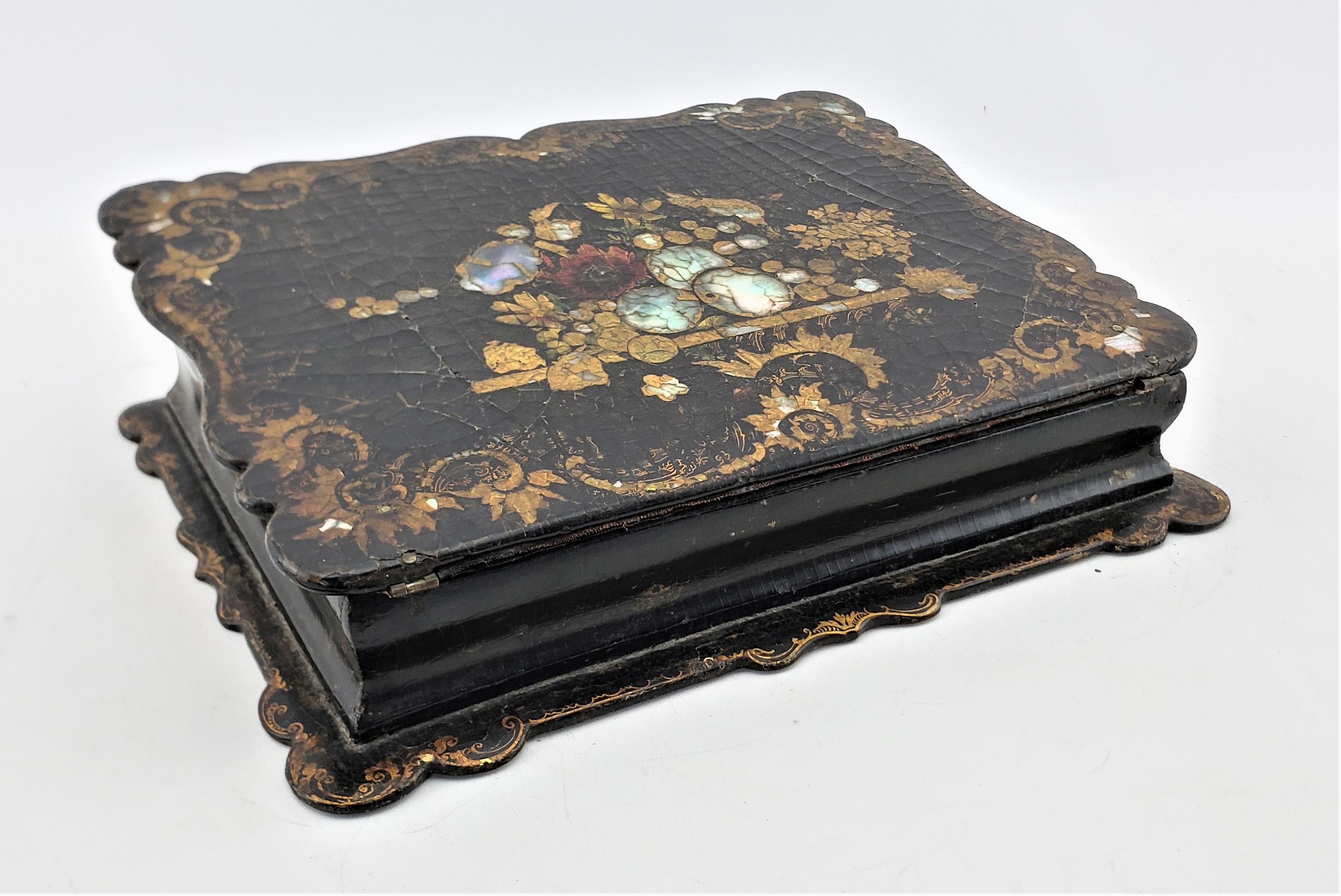 This antique writing box or lap desk was made by the highly renowned Jennens & Bettridge of England in approximately 1880 and done in the period Victorian style. The box is constructed of paper mache which has been treated with a lacquer finish or
