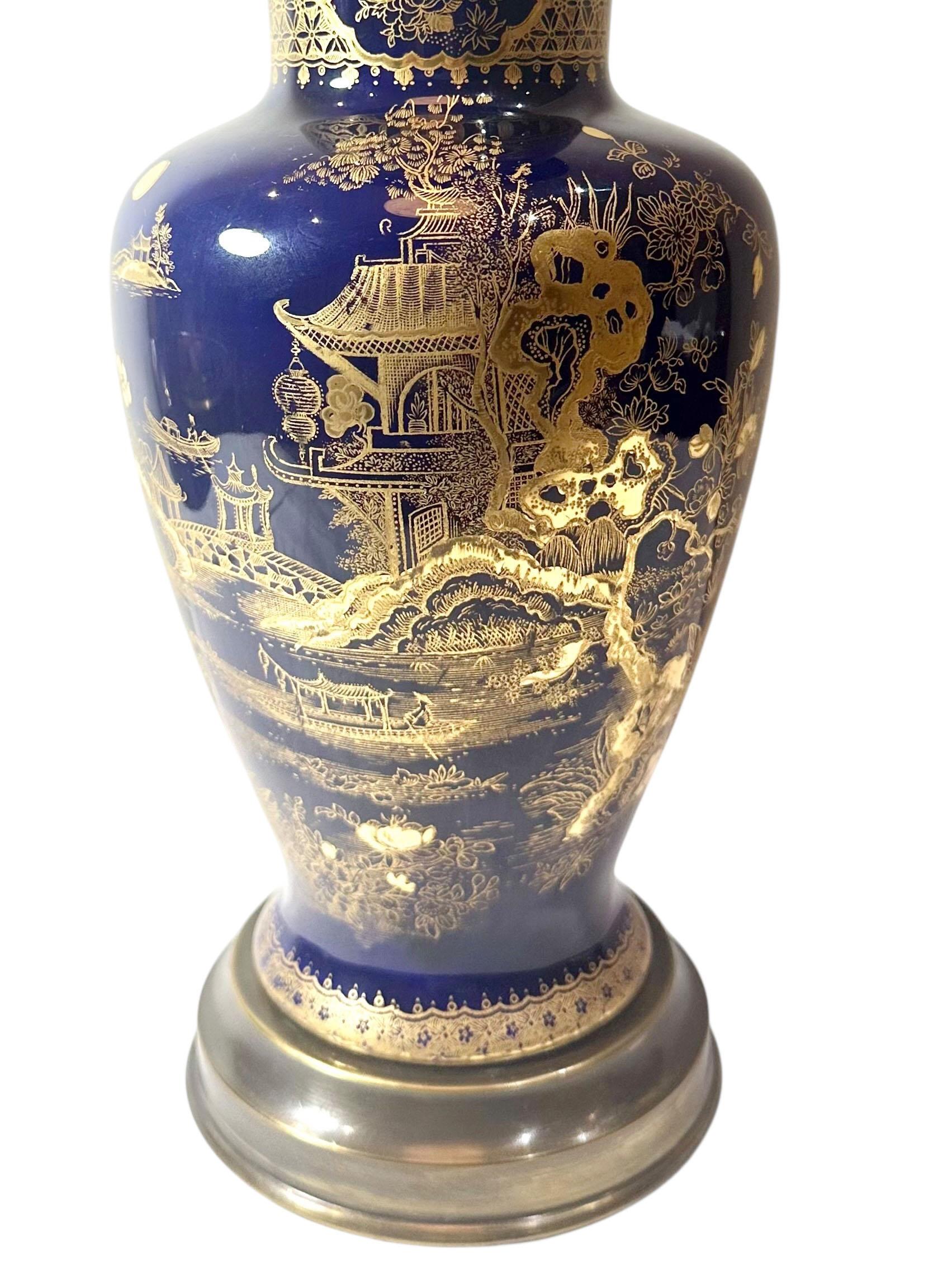 Très belle lampe ancienne de Stoke on Trent Antiques datant du début du siècle. Le corps est fabriqué en porcelaine bleu royal profond, richement décorée d'accents dorés appliqués à la main. Elle repose sur une base en bronze et comprend une douille