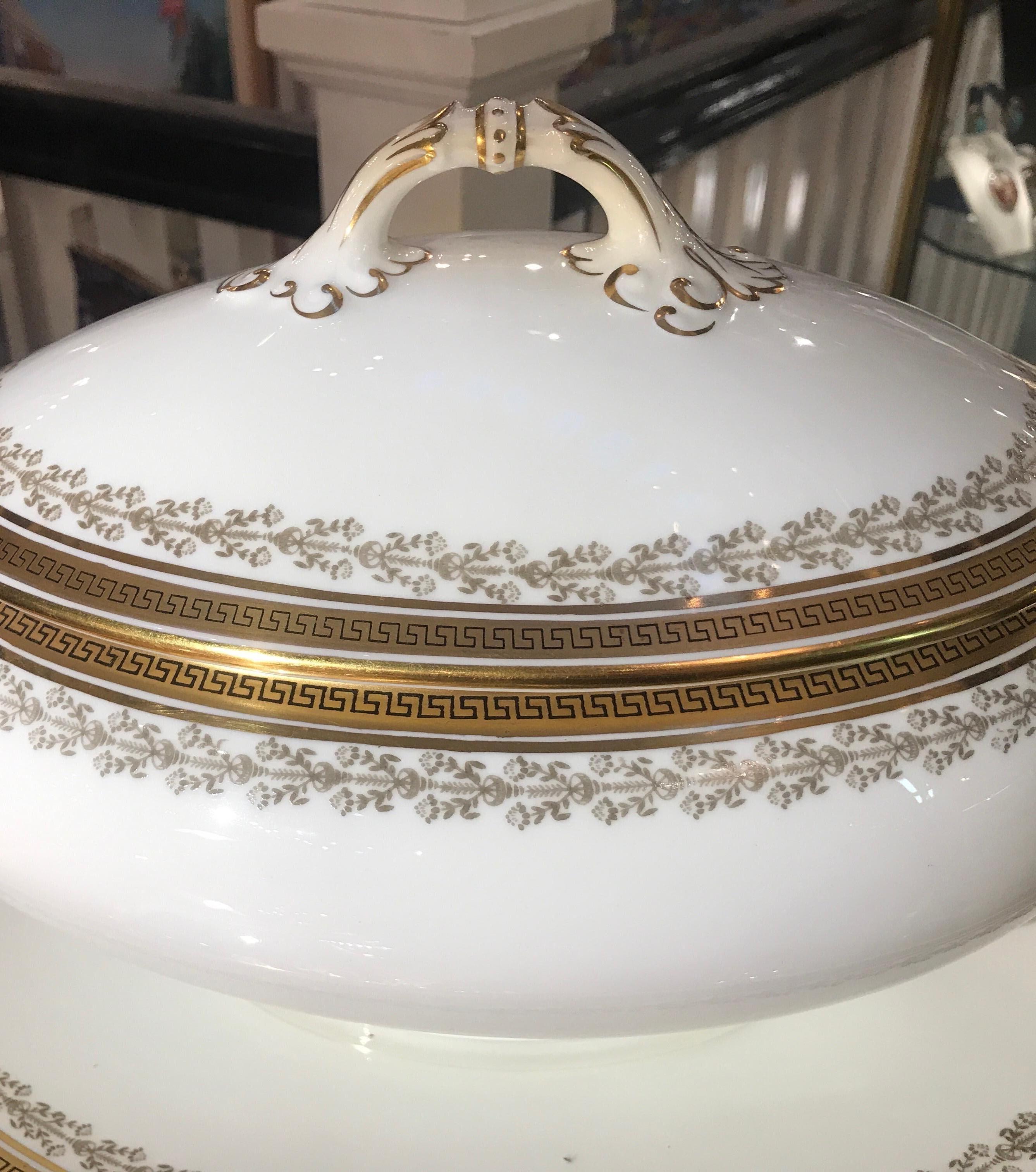 Elegant large soup tureen with oval underplate. England, circa 1910 made by Cauldon. The white porcelain with gilt Greek key decoration on the lid, tureen and underplate. The Classic white and gold will complement almost any dinnerware service.