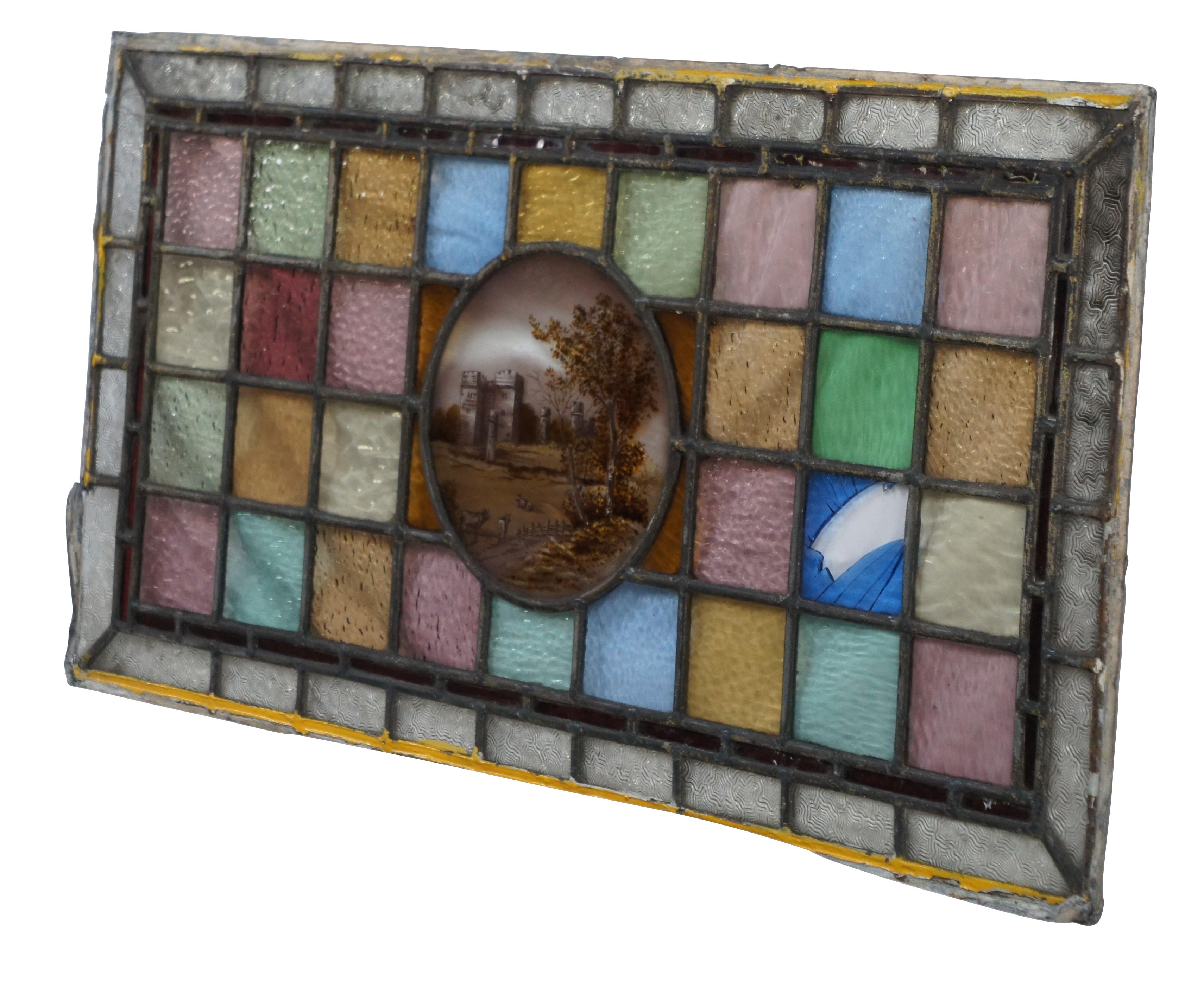Intriguing antique English leaded stained glass transom window panel.  Features a colorful gridded design with a central hand painted castle landscape with pastoral cows.   

Dimensions:
17