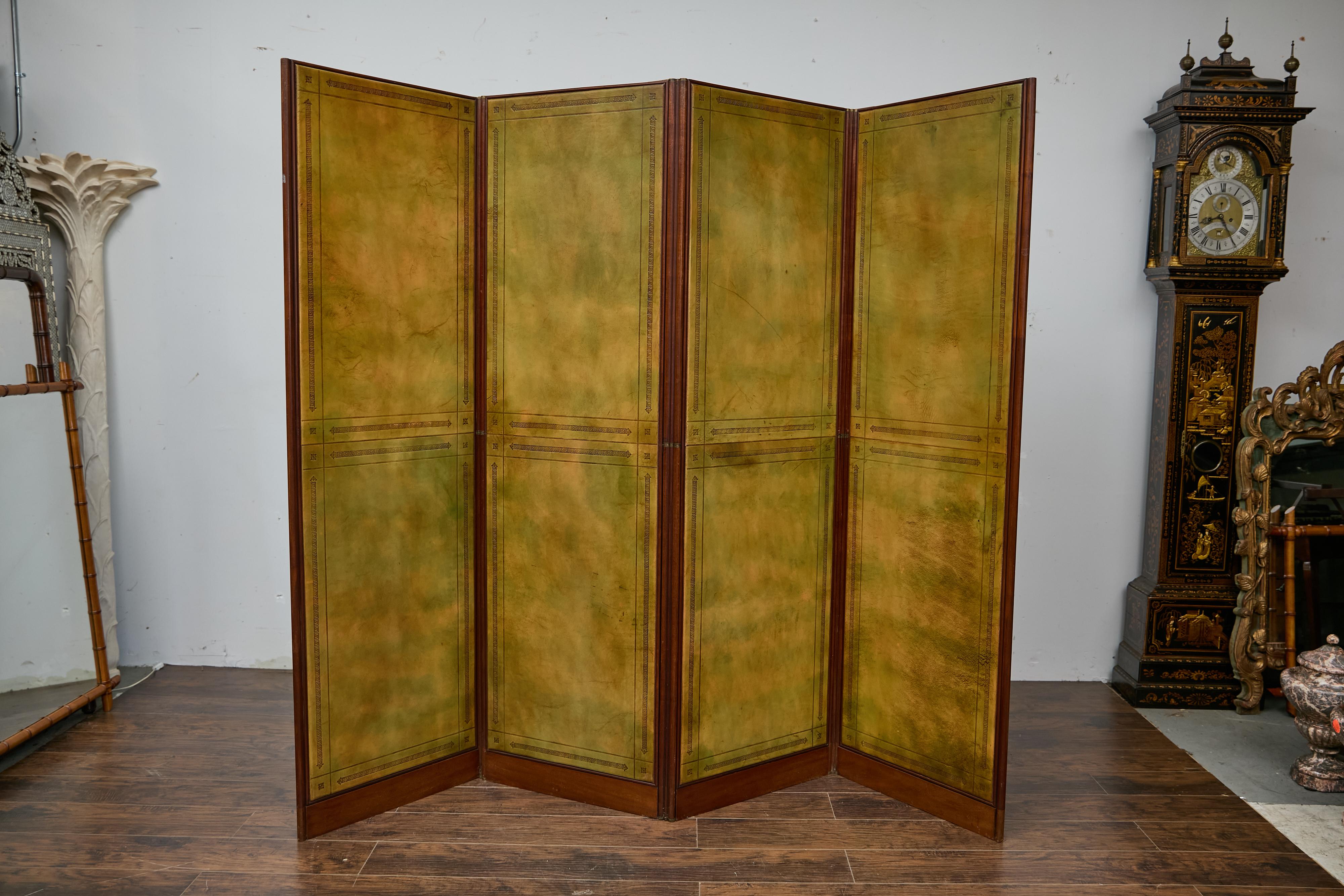 Questo paravento inglese di fine secolo a quattro pannelli in pelle, risalente al 1900 circa, è una dichiarazione di antico artigianato ed eleganza classica. Ogni pannello è rivestito in pelle tinta a mano nei toni del verde caldo e dell'ocra,