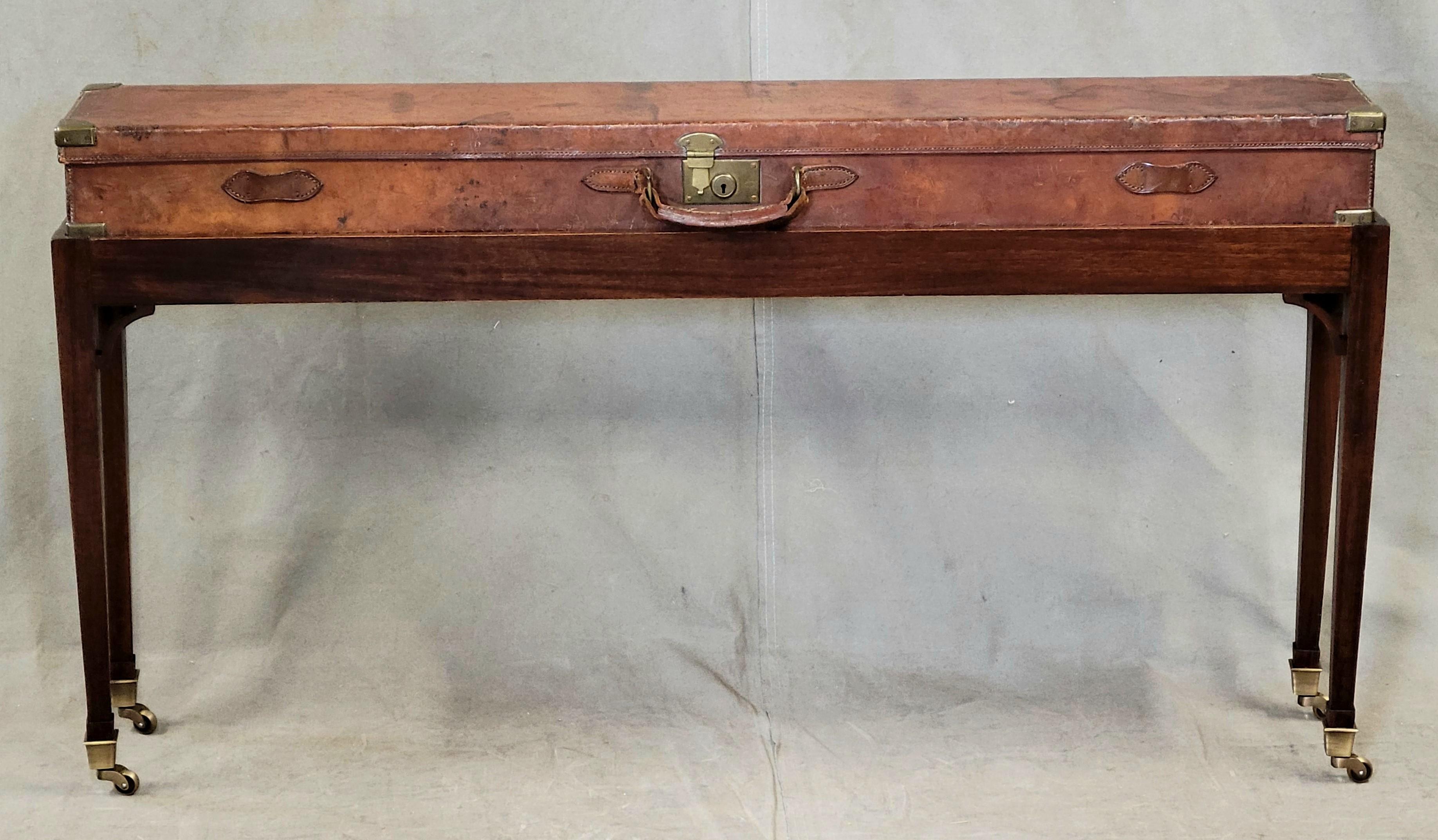 A unique and charming English console table created out of a circa 1900 leather rifle case mounted on a custom fit mahogany and brass stand. Rifle case label reads, 