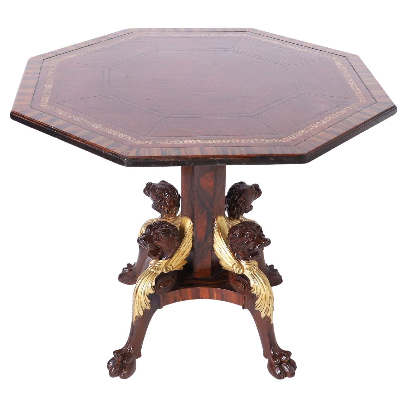 Handsome English center table with an octagon tooled brown leather top crossbanded in rose wood on a rosewood pedestal and base with carved mahogany lion heads in gilt wings and acanthus leaves on paw feet.